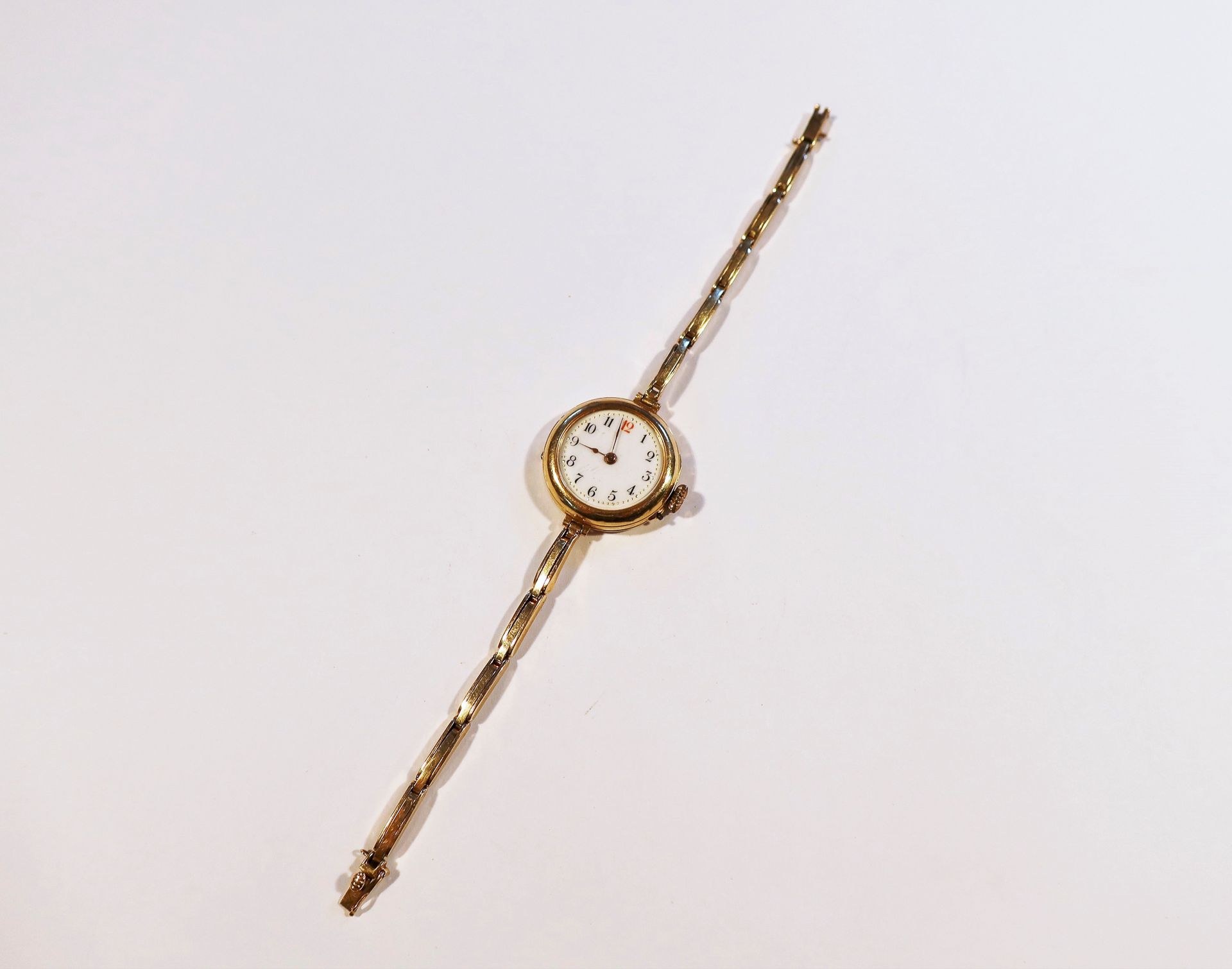 Montre bracelet pour femme en or 18K (750), cadran en émail blanc, index chiffres arabes formant les heures, mouvement à remontage mécanique, bracelet en or 18K.

Poids brut : 18,4 g