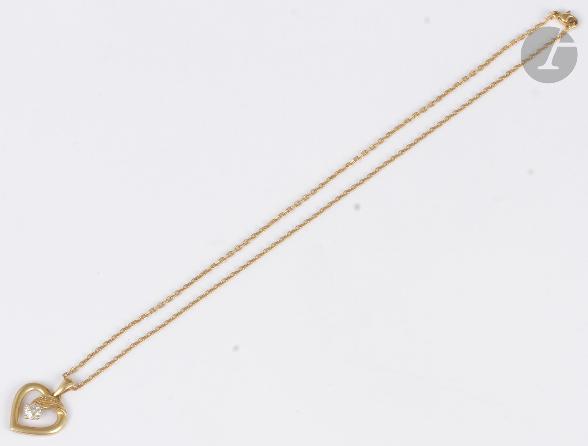 Pendentif en or 18K (750) en forme de cœur, serti d’un diamant de taille ancienne, coulissant sur une chaîne en or 18K.

Poids brut : 6,3 g