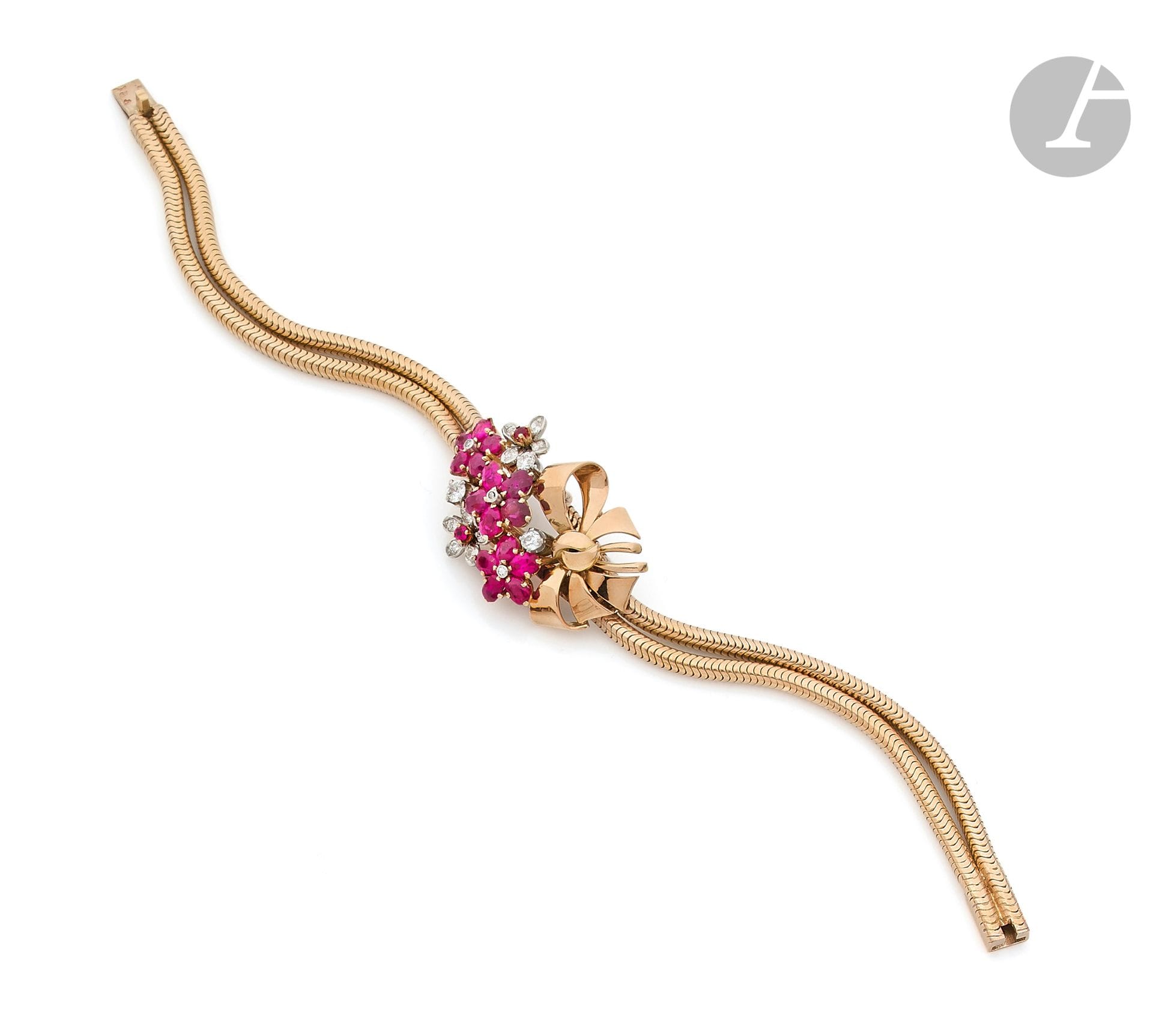 Bracelet en or 18K (750 ‰), orné d’un motif fleuri serti de rubis ovales et ronds, agrémenté de diamants ronds de taille ancienne et 8 / 8, bracelet en double chaînette serpent en or 18K. Travail français des années 1960. Longueur : 19,8 cm environ. Poids brut : 40,3 g