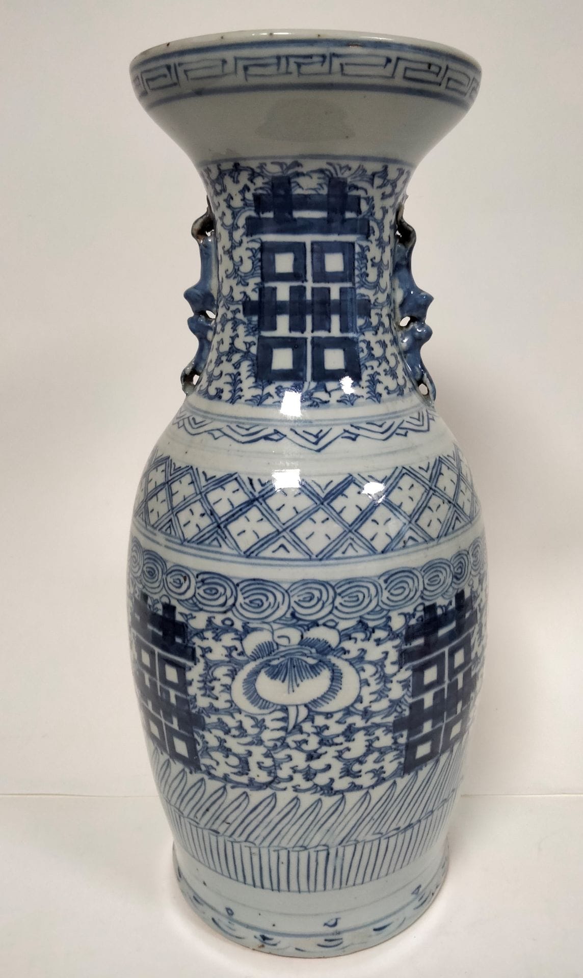 CHINE, XXe siècle
Paire de vases en porcelaine à décor bleu blanc de caractères de double bonheur et de frises de grecques sur fond de rinceaux, prises en forme de double chimère.   
Hauteur : 45 cm
Éclats et fêles au col, restaurations.