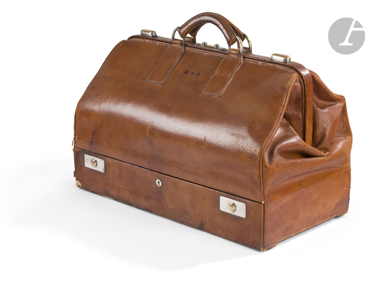 S.T.DUPONT  8 bis rue Dieu Paris
Grand sac mallette en porc naturel (vide, taches, accidents et manque les clefs), chiffré M.H.B., garniture en métal argenté, début du XXème siècle
59 x 30 x 36 cm