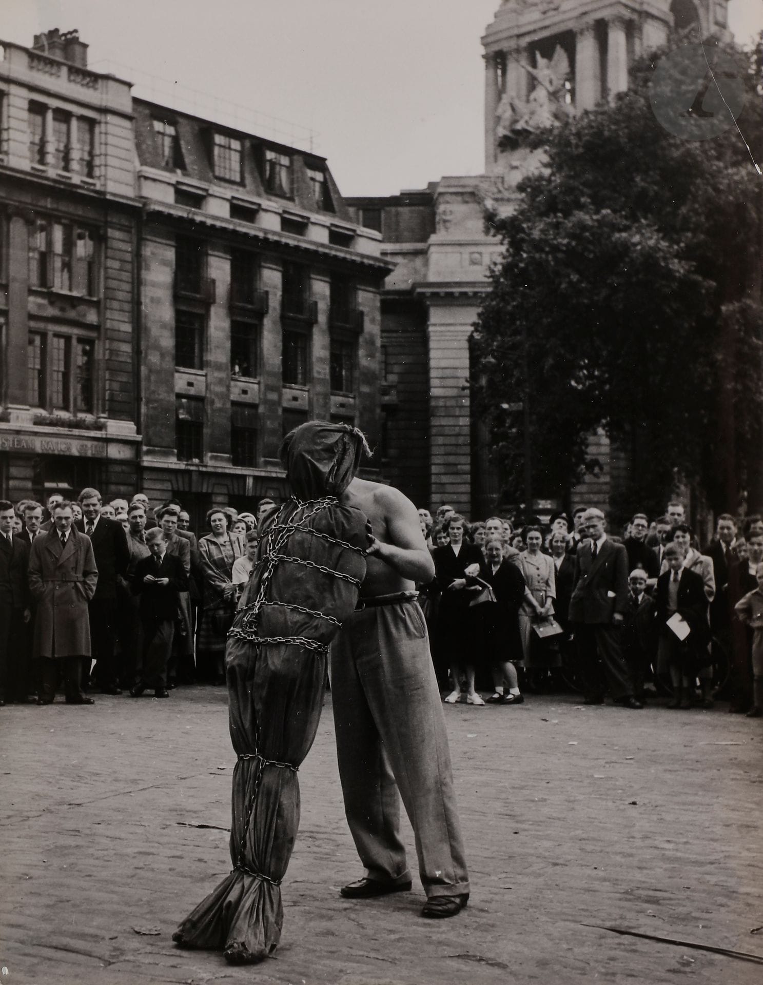 Izis (Israëlis Bidermanas, dit) (1911-1980)
Londres, c. 1950. 
Spectacle de rue.
Épreuve argentique d’époque. Tampon « Photo Izis » et annotation manuscrite au verso.
28,5 x 22 cm

Izis (Israelis Bidermanas, known as) (1911-1980)
London, c. 1950. 
Street performance.
Vintage gelatin silver print. Stamp "Photo Izis" and handwritten annotation on verso.
28.5 x 22 cm