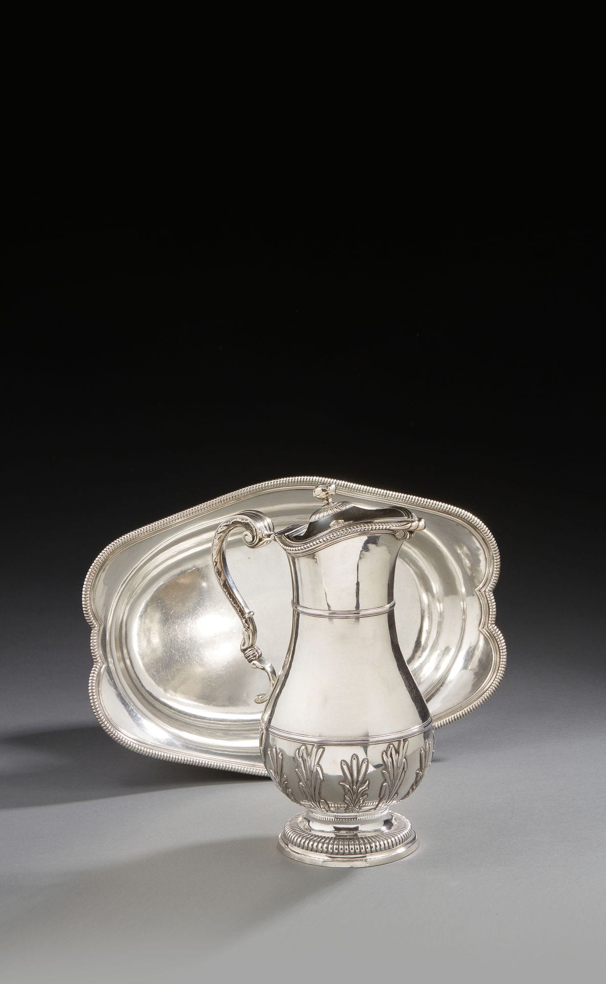 
TOULOUSE 1744



Ewer and its silver basin. The basin of oval form with contours is moulded of godrons. The ewer rests on a pedestal with gadroons, the baluster body receives in the lower third a decoration of reeds of two sizes ended by a rush, the latter in recall under the neck. The hinged lid is bordered with gadroons like the terrace topped by a rose. The scrolled handle is set on shells in applique, it is decorated on the side with rocaille falls. 



Master silversmith: Louis Ist SAMSON, received in 1715



Weight: 1876,4 g - dimensions of the basin: length: 33 cm - width: 22,8 cm, height of the ewer: 25 cm



COAT OF ARMS ON THE EIGUIERE AND THE BASIN