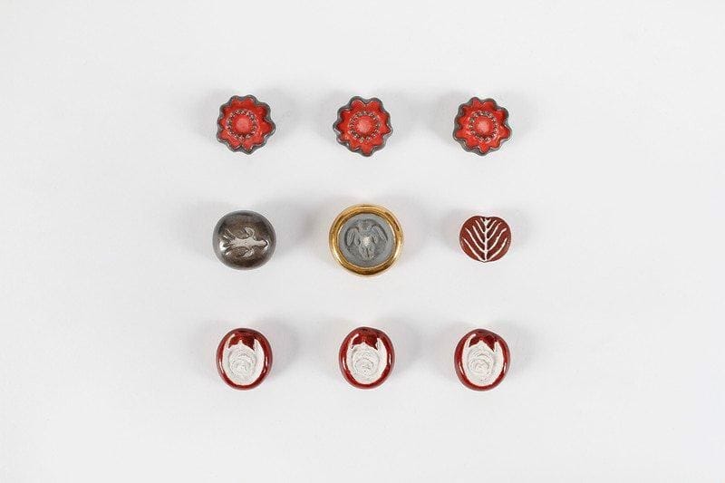 Line VAUTRIN (1913-1997)
Lot de neuf boutons en céramique émaillée. Trois boutons « Fleur », entourage bordeaux, monogrammés. 2,9 x 2,6 cm. Un bouton « Colombe » argent, monogrammé. D.: 2,5 cm. Modèle référencé sur le site dédié à l'artiste. Un bouton « Angelot » gris et doré, monogrammé (une égrenure sur le ventre de l'angelot). D: 3,4 cm. Un bouton « Arbre de vie » bordeaux, non signé. D.: 2,2 cm. Modèle référencé sur le site dédié à l'artiste. Trois boutons « Fleur » rouge et argent, monogrammés. D.: 2, 8 cm.