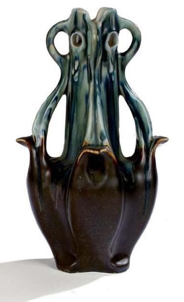 BRUERE (GDV)
Important vase organique en porcelaine émaillée vert et brun. Corps a panse renflée, col polylobé et orné de perforations, anses mouvementées en prolongement de la base. Décor en relief de gouttes en chute des parties ajourées. Circa 1900. Signé sous la base. Hauteur: 36,5 cm Bibliographie: « The Paris Salons 1895-1914, volume IV: céramics & glass » par Alastair Duncan. Editions Antique Collectors'Club. USA 1998. Modèle à rapprocher reproduit sur une photographie d'archive page 73.