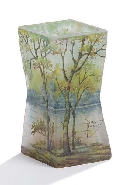 DAUM Nancy France
Vase losangique diabolo. Épreuve en verre dégagé à l'acide à décor émaillé d'un paysage lacustre bordé d'arbres. Deux infimes éclats en pourtour de la base. Signature écusson émaillée. Hauteur: 11 cm