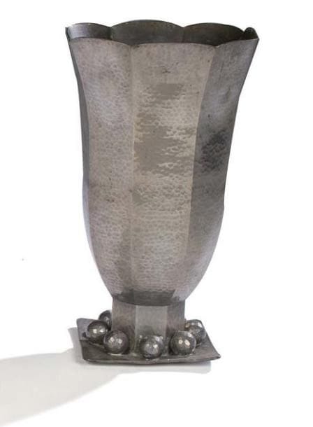 Jean DESPRES (1889-1980)
Important vase tulipe réalisé en dinanderie d'étain à surface entièrement martelée. Base à pans coupés, ornés de sphères facettées, reposant sur une terrasse de section carrée. Travail des années 1930/40. Signé à la pointe à deux reprises, sur et sous la terrasse. Hauteur: 34,5 cm Provenance: Acquis directement auprès de l'artiste par la famille avallonnaise des actuels propriétaires.
