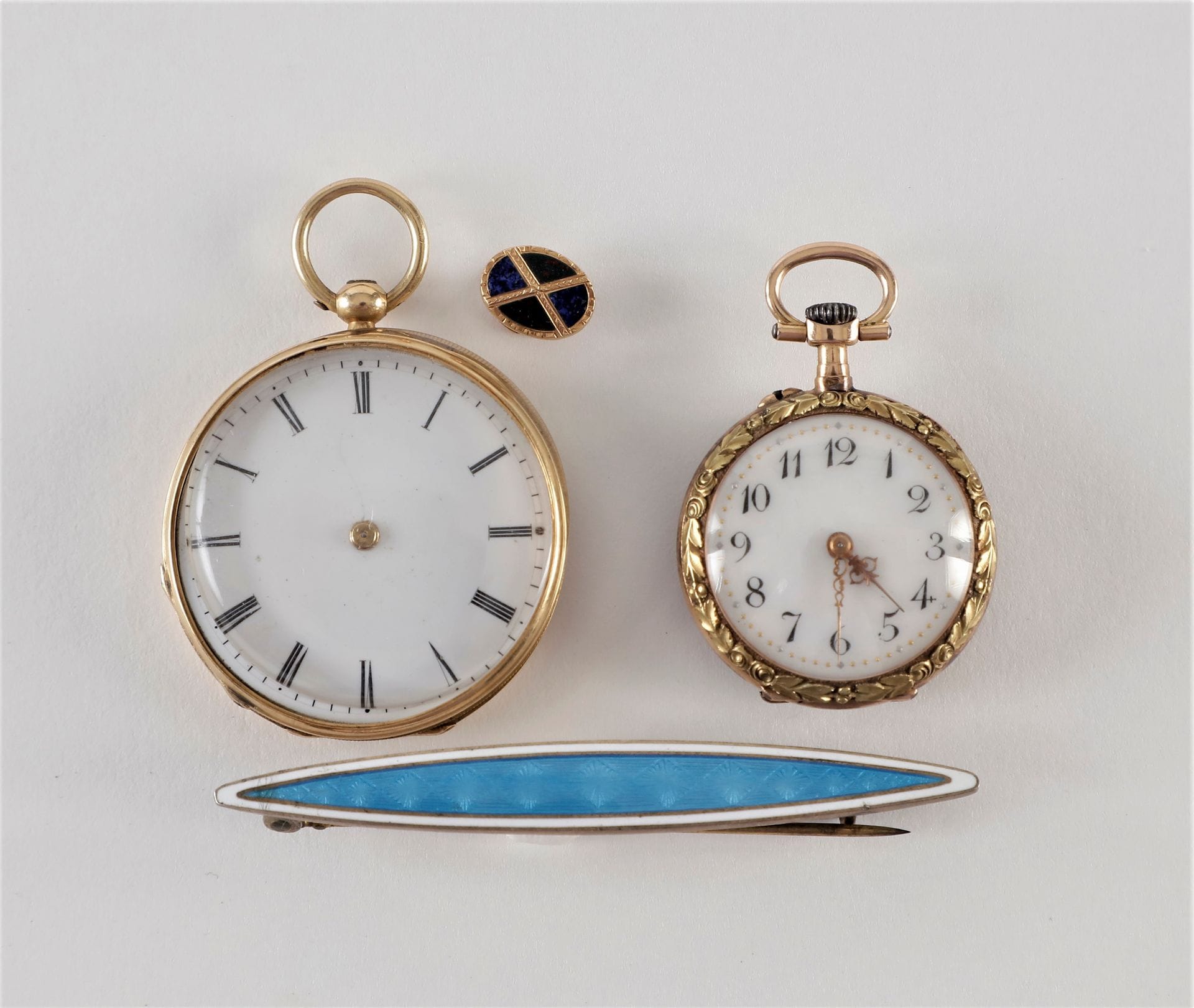Lot de deux montres de col en or (18K) avec cuvettes en or. Poids brut : 36,33 g 
(aiguilles manquantes sur l'une; l'autre Lecoultre).
On joint un petit bouton de col en or (18K) avec pierres dures 
et une broche barette en argent doré émailée bleue.