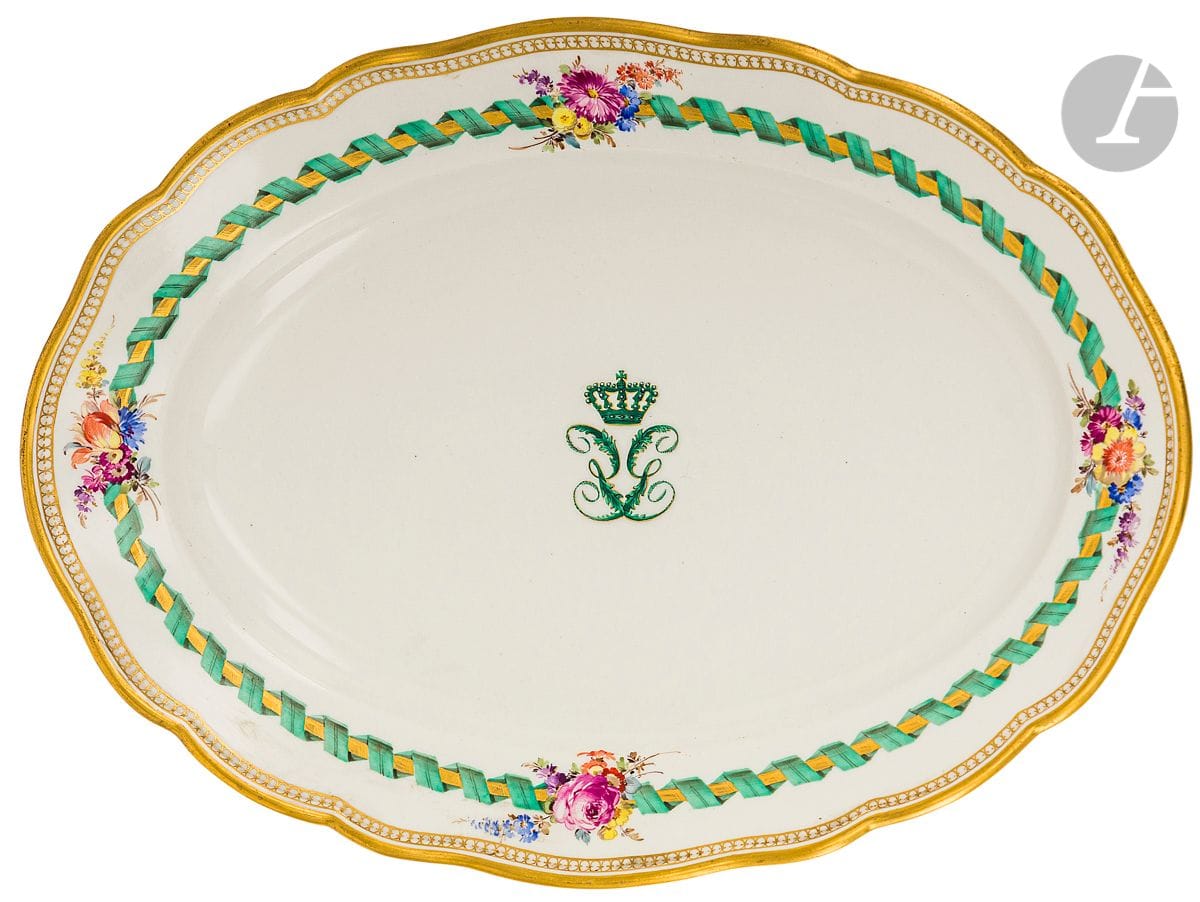 Meissen
Plat ovale en porcelaine à bord contourné à décor polychrome au centre d’un monogramme et sur l’aile de rubans et bouquets de fleurs.
Marqué : épées croisées en bleu.
Fin du XIXe siècle. 
L. 34 cm