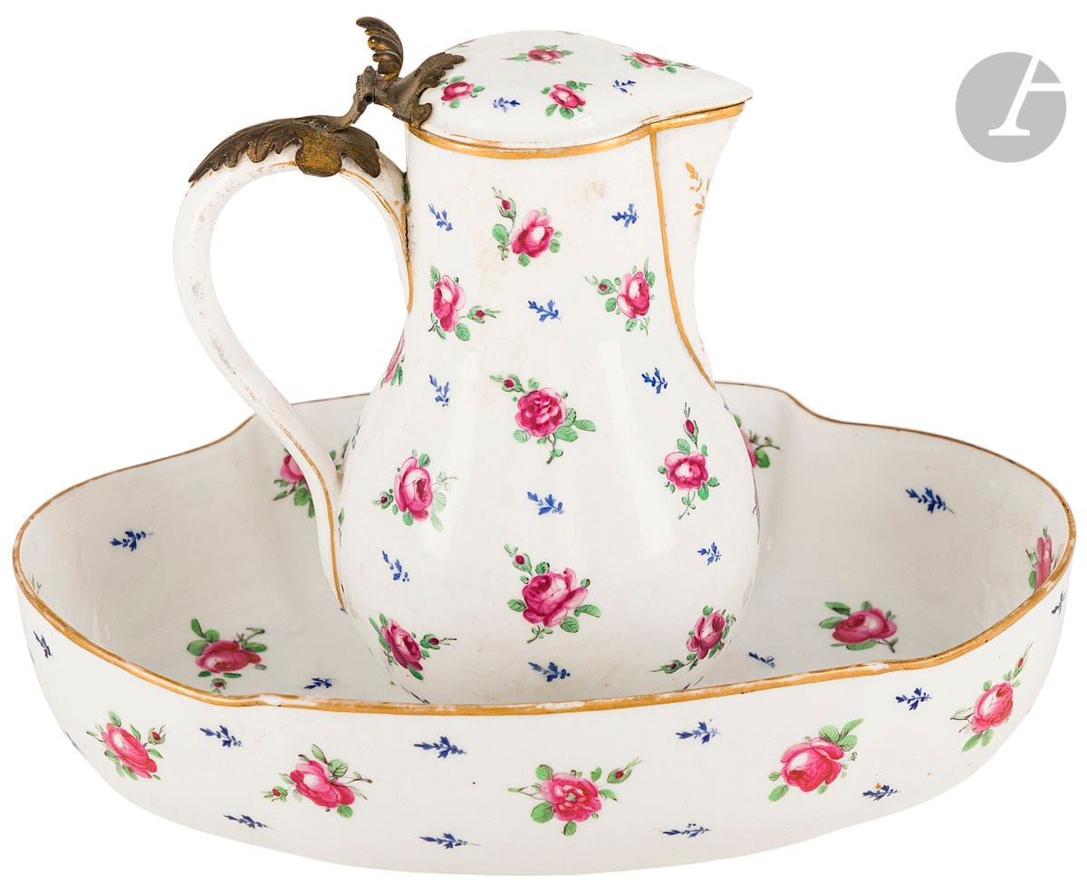 Paris
Pot à eau couvert et son bassin ovale en porcelaine à décor polychrome de semis de roses.
Monture du couvercle en métal doré.
Marqués : A couronné en rouge, manufacture de la Reine, rue Thiroux
XVIIIe siècle. 
H : 21 cm, L : 30,5 cm
Fêlure restaurée sur le bassin.