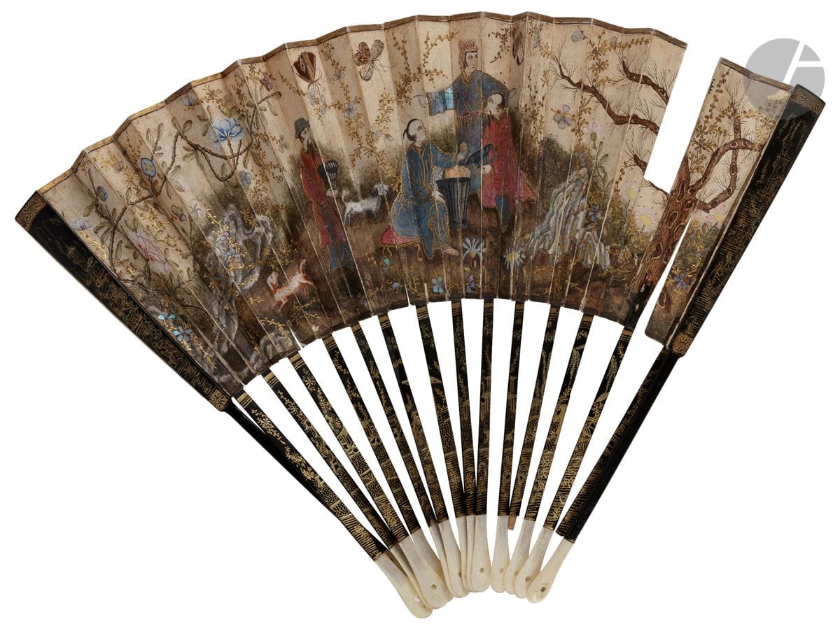The Fruit Harvest, Europe, ca. 1770-1780
Folded fan, the paper sheet painted with gouache of a garden scene in the Chinese taste. Three servants in a garden present a harvest of fruit to a figure. All are dressed in burgau or applied mother-of-pearl plates. Flowers in applied mother-of-pearl and butterflies in natural feathers enliven the composition.
The reverse side in mute paper.
Black lacquered bamboo frame with gold decoration of figures in a garden. The head in ivory*. 
 H.t. 29,5 cm H.f. 14,7 cm (missing, accidents)
With a fan box covered with paper in imitation of shagreen. 18th century
