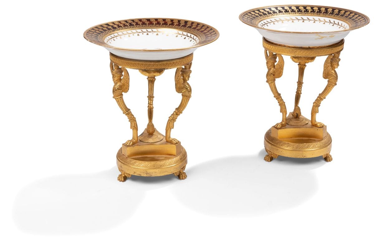*Paire d’assiettes en porcelaine de Sèvres sur des montures de bronze doré à décor guilloché, les montants en trépieds à figures de Victoires, reposant sur une base circulaire à pieds en griffe ; la paire d’assiettes en porcelaine de Sèvres (associées) à décor en or de feuillages, rosaces et frise de postes sur fond peint à l’imitation de l’écaille d’époque Empire, 1808 (accidents et restaurations).
Époque Restauration (composite).
H : 26 cm, D : 23,5 cm