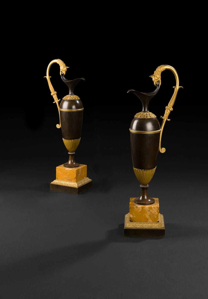 *Paire d’aiguières en bronze patiné et bronze doré, les anses à tête de griffon, reposant sur une base en marbre jaune de Sienne et un contre-socle en bronze doré à décor de frise feuillagée ; (petits accidents).
Attribuée à Antoine Ravrio.
Époque Empire.
H : 55 cm
