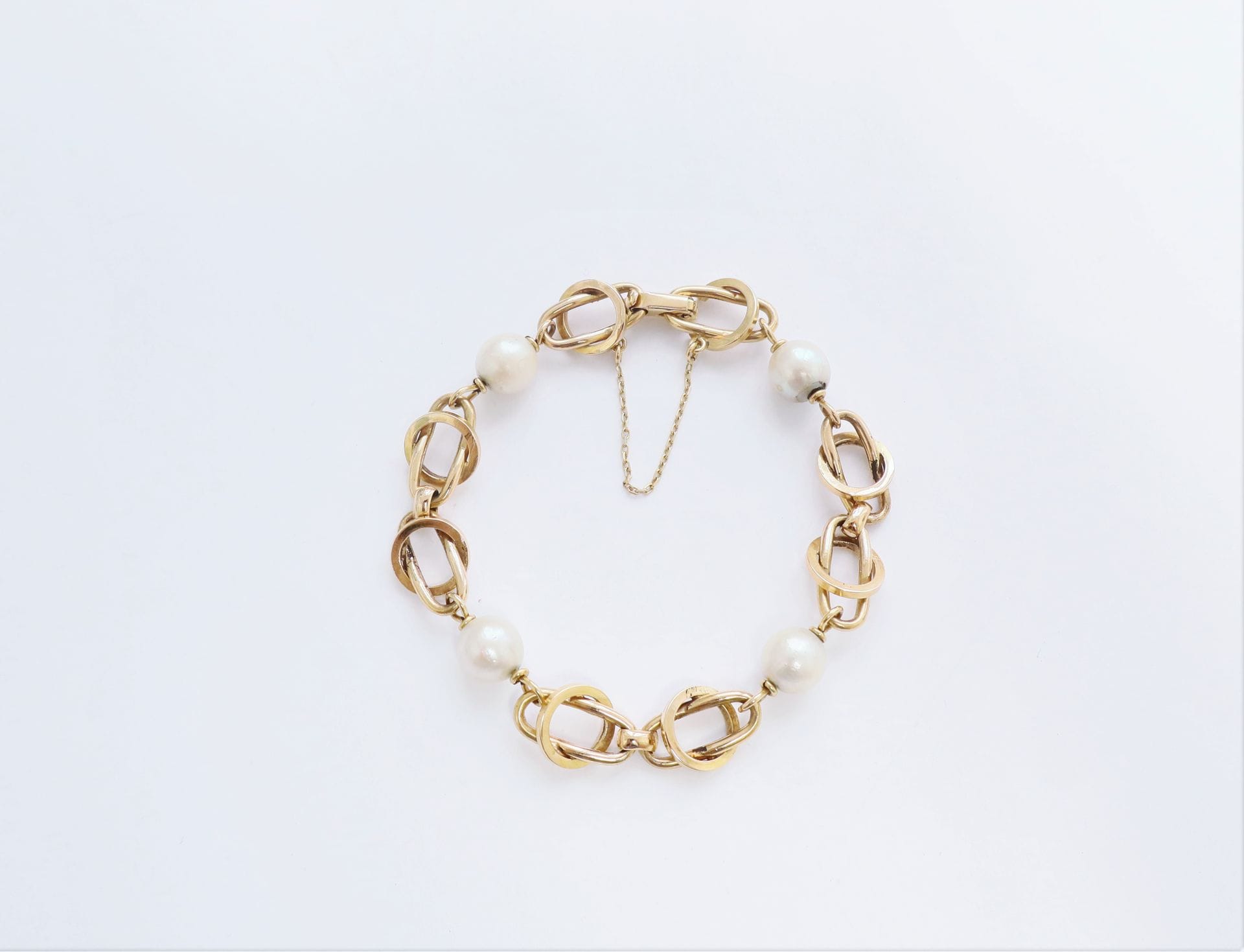 Bracelet en or 18K (750), ponctué de 4 perles de culture. Longueur : 18,5 cm environ. Poids brut : 15,3 g