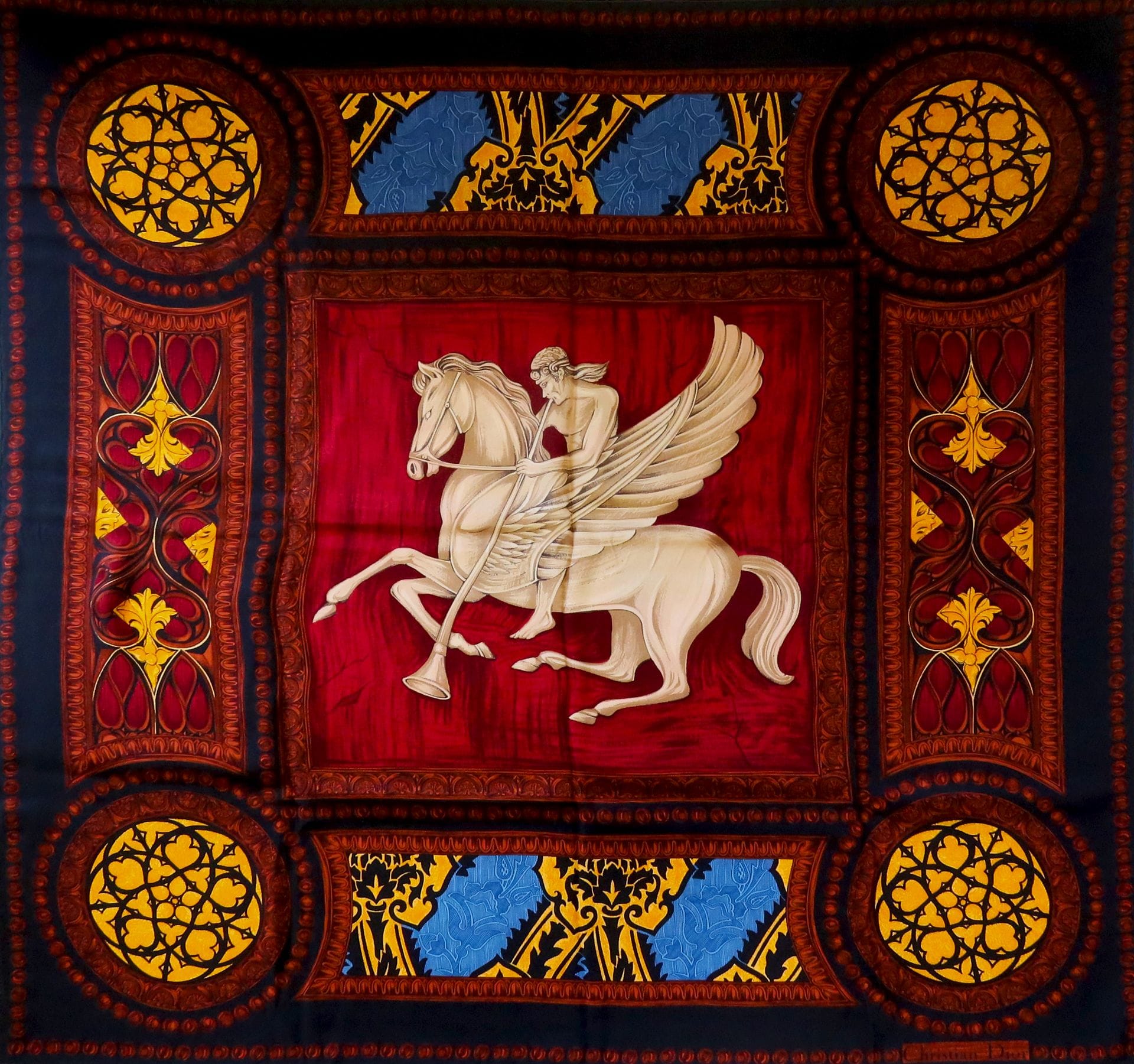 Lot de trois foulards en soie dont un Christian DIOR à décor d'un cavalier sur cheval ailé, un Must de Cartier à fond rouge damassé à décor de pierres précieuses et flamands roses, le dernier Korloff dans les tons jaunes et noirs.