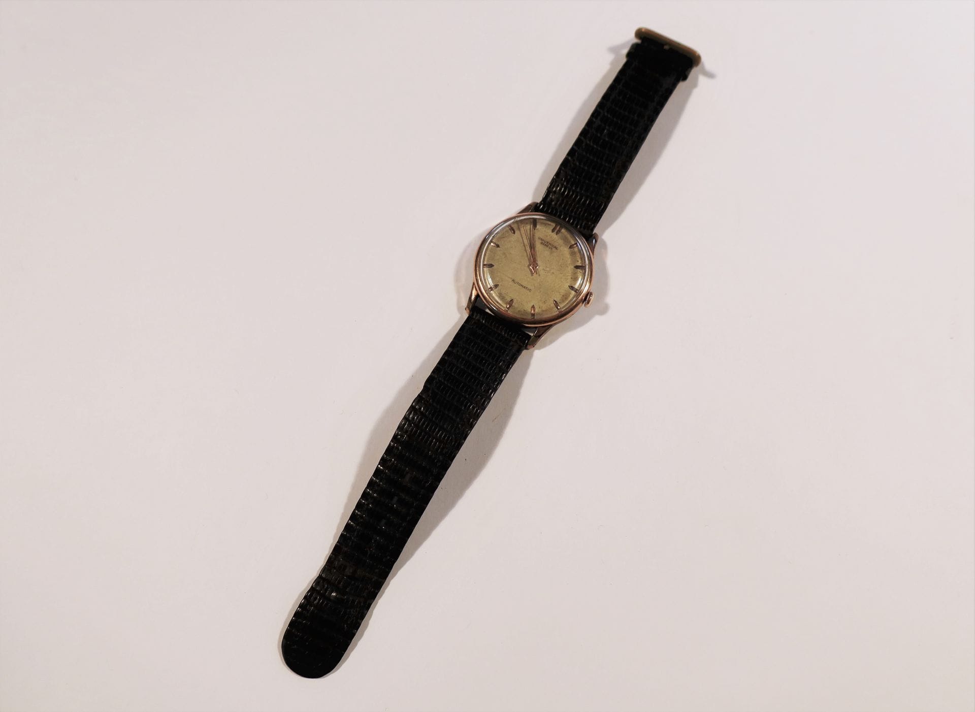 UNIVERSAL 

N°1290364

Men's wristwatch in gilt metal, white dial (piqué), applied baton hour markers, mechanical movement.