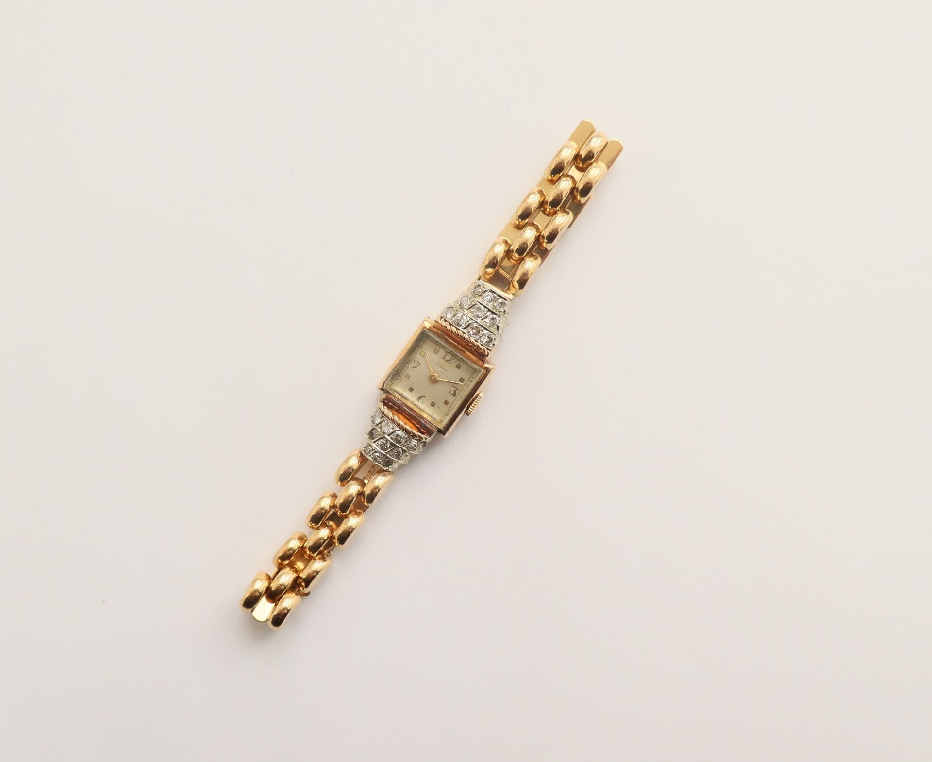 HAMOR

N° 2184

Ladies' wristwatch in 18K (750) gold, diamond-set bezel, white dial, mechanical movement, 18K gold bracelet.

Gross weight: 25.8 g