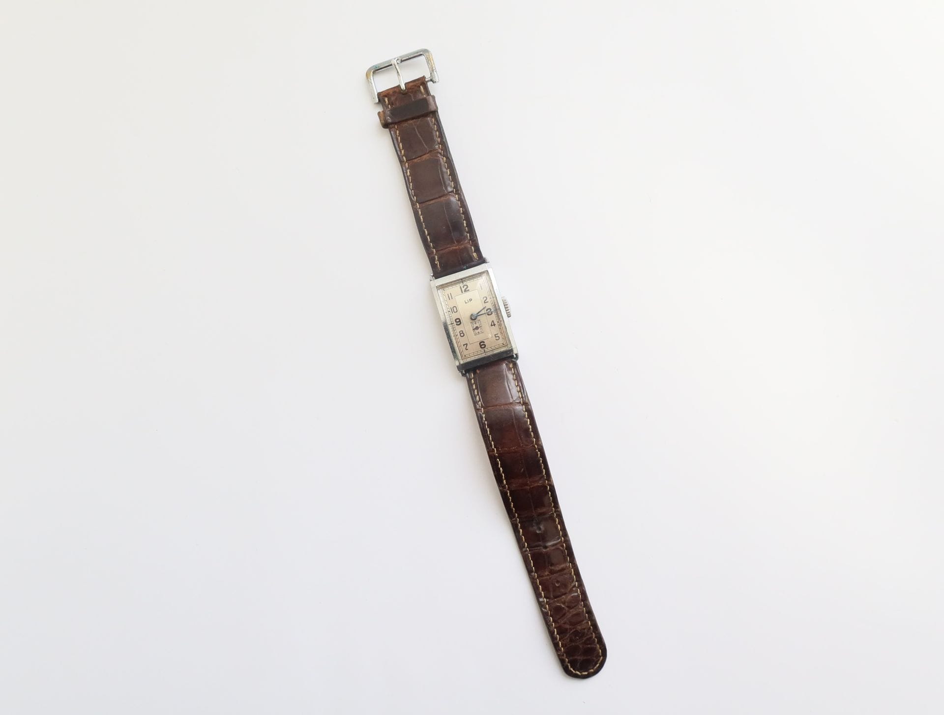 LIP

Men's stainless steel wristwatch, white dial, Arabic hour markers, second hand at 6 o'clock, winding movement, leather strap.