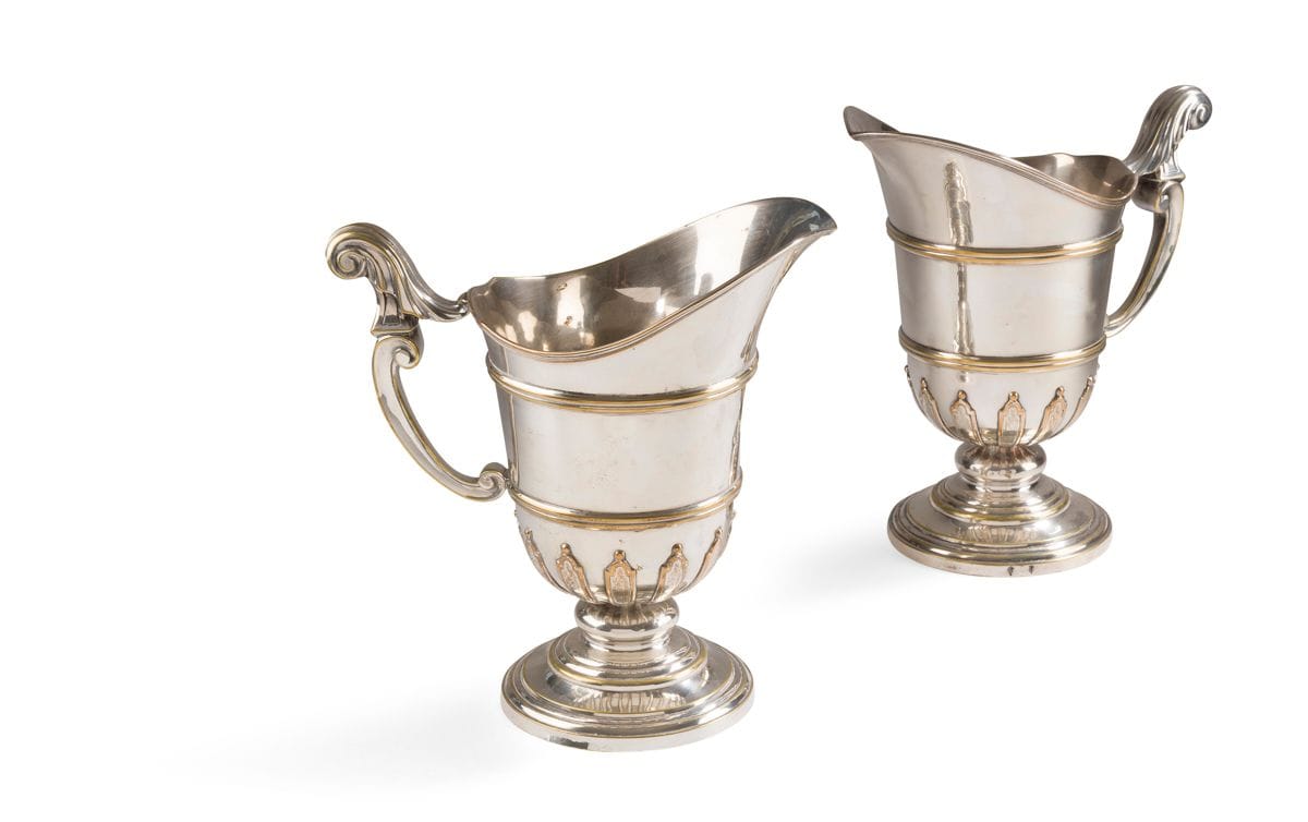 FRANCE XVIIIe SIÈCLE
Paire d’aiguières casque à appliques en métal plaqué (réargentée), elle repose sur un piédouche circulaire, le corps rehaussé d’appliques et souligné de deux joncs de filets.
Hauteur : 27 cm – diamètre : 13,4 cm
État : réargentée, piédouche changé
