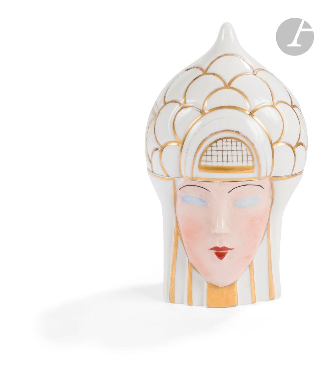 LIMOGES FRANCE 
Tête de femme, déclinaison du n°218 Ter de la Maison ROBJ Paris
Boîte à bonbons. Épreuve en porcelaine émaillée polychrome et à l’or au four. Un petit éclat sur la réception du couvercle au dos et usures à la dorure. Marquée LIMOGES France à l’or sous la base. H : 21 cm 

Bibliographie : 
- Catalogue commercial Robj – 1928. Modèle original par la maison Robj reproduit planches 15.
