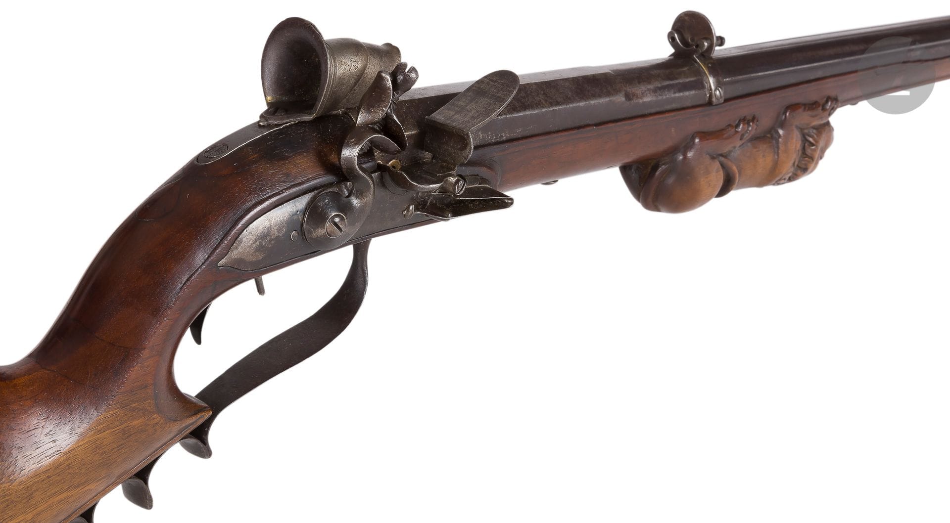 Carabine de tir à silex du type « grenobloise », un coup, calibre 16 mm 
Canon de 83,5 cm, rond, à arrêtes, à pans au tonnerre, avec traces de signature.
Bouche rectangulaire à âme ronde. 
Tunnel de visée zoomorphe, œilleton ajouré et point de mire.
Platine démontable à la main et chien à corps rond. Double détente Steicher.
Pontet en fer avec prise doigt. 
Monture en noyer, fût sculpté sur le dessous d’un lion allongé. Crosse à busc plat. 
Longueur : 120 cm
A.B.E. (Traces d’usage). Vers 1780.

