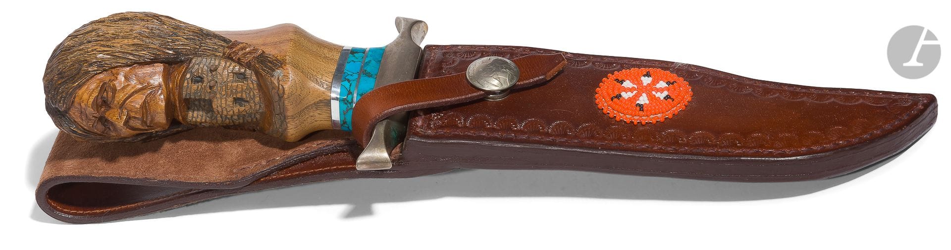 Couteau indien type bowie. 
Poignée en bois sculpté en ronde bosse d’une tête indienne, virole ornée de turquoises, garde en métal blanc. Lame à dos et contre tranchant de « Bob Dill » (Colorado). Dans son fourreau en cuir orné d’une rosace perlée. 
B.E. XXe siècle.

