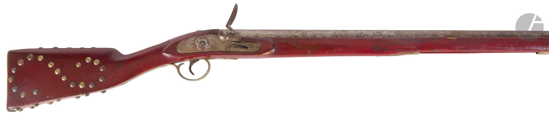 Long fusil à silex de traite ou « de boucanier » 
Long canon rond de 131cm, poinçonné.
Platine à corps plat (manque le chien).
Garnitures, pièce de pouce et cloutage de crosse en laiton.
Fût, crosse et baguette, entièrement laqué rouge.
Longueur totale : 173 cm
A.B.E. (Oxydation). Fin du XVIIIe siècle.

