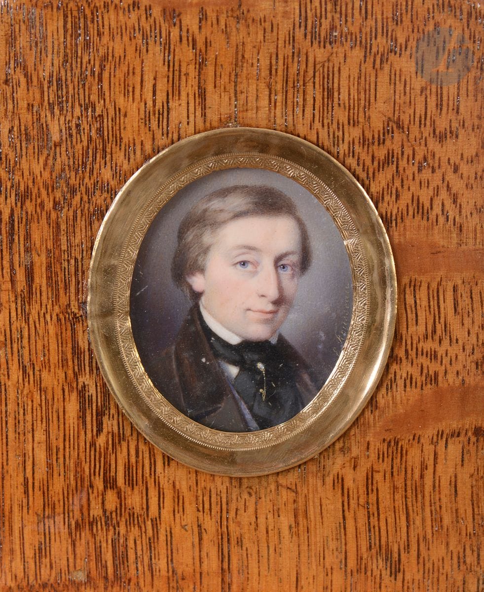 Edmé ROUSSEAU (Paris, 1815- Paris, 1858)
Portrait de jeune homme blond en buste de trois-quarts à droite en costume marron à col de velours, ruban bleu ou gilet bleu, une épingle en or piquée dans sa cravate noire
Miniature ovale sur ivoire 
Signée à droite « E. Rousseau »
4,1 x 3,3 cm à vue
Cadre en bois naturel vernis rect. 9,8 x 7,8 cm
Poids brut : 29.6 g