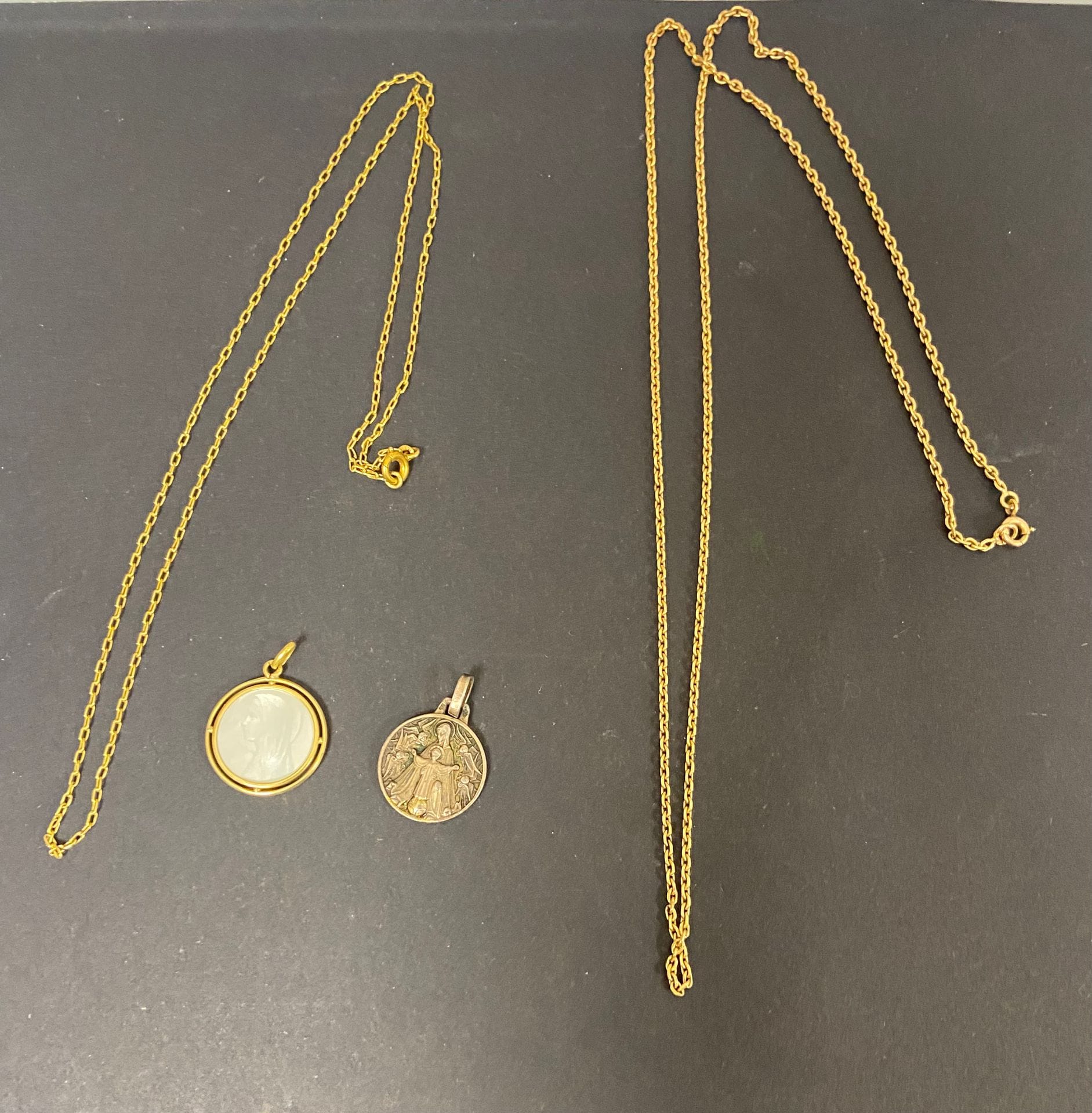 
Lot de bijoux en or (18K).. Poids brut : 12,49 g 

- deux chaines en or jaune (18K). Poids : 8,3 g

- 1 médaille en nacre sertie d'or (18K). 



On joint une médaille en argent (2,7 g)
