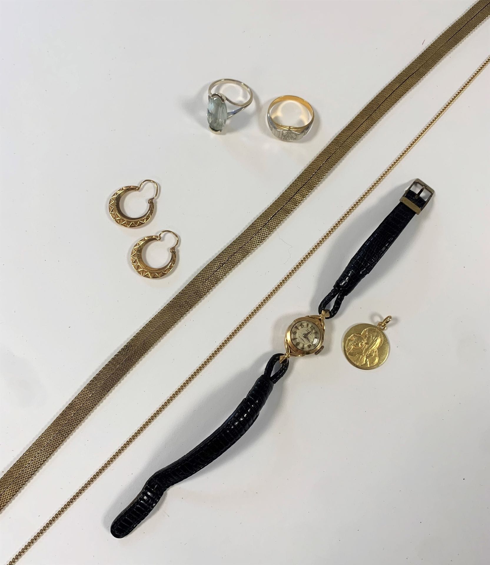 Lot de bijoux en or (18K et 14K). Poids brut: 70,9 g 
- une chaîne, une médaille mariale, 1 paire de créoles, 1 chevalière. Poids : 13,8 g 
- une bague en or gris sertie d'une pierre bleue. Poids brut : 4,69 g 
- une montre de dame en or (18K). Poids brut : 10 g
- un collier souple en or (14K). Poids : 42,3 g