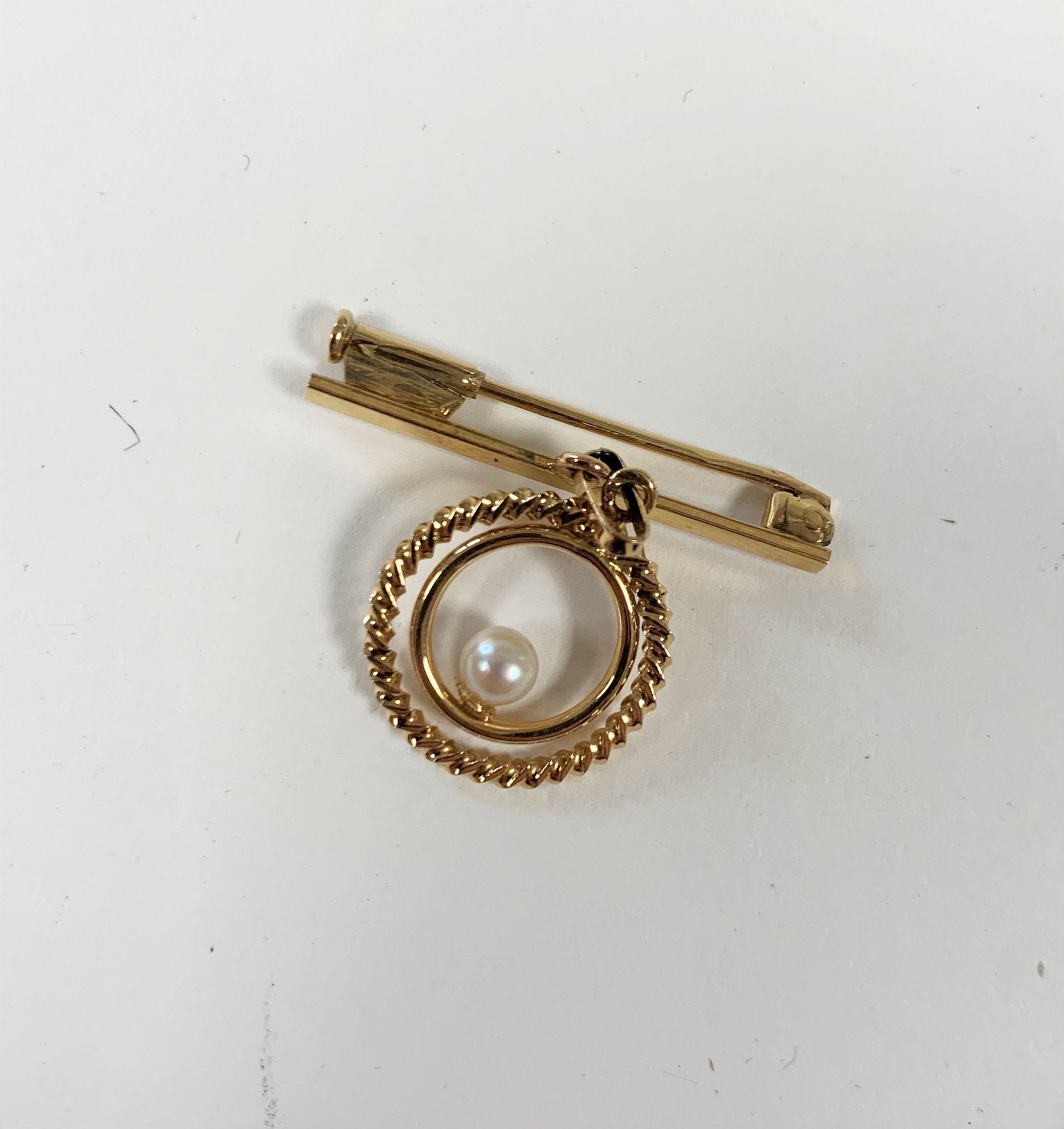Broche en or (18K) jaune retenant un motif rond orné d'une perle de culture. Poids brut : 2,5 g
Etui joint.