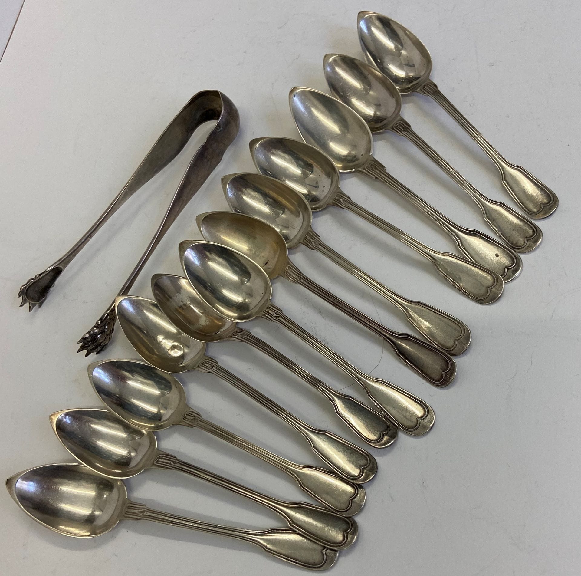 12 petites cuillères  et une pince à sucre, en argent. Poids: 257 g