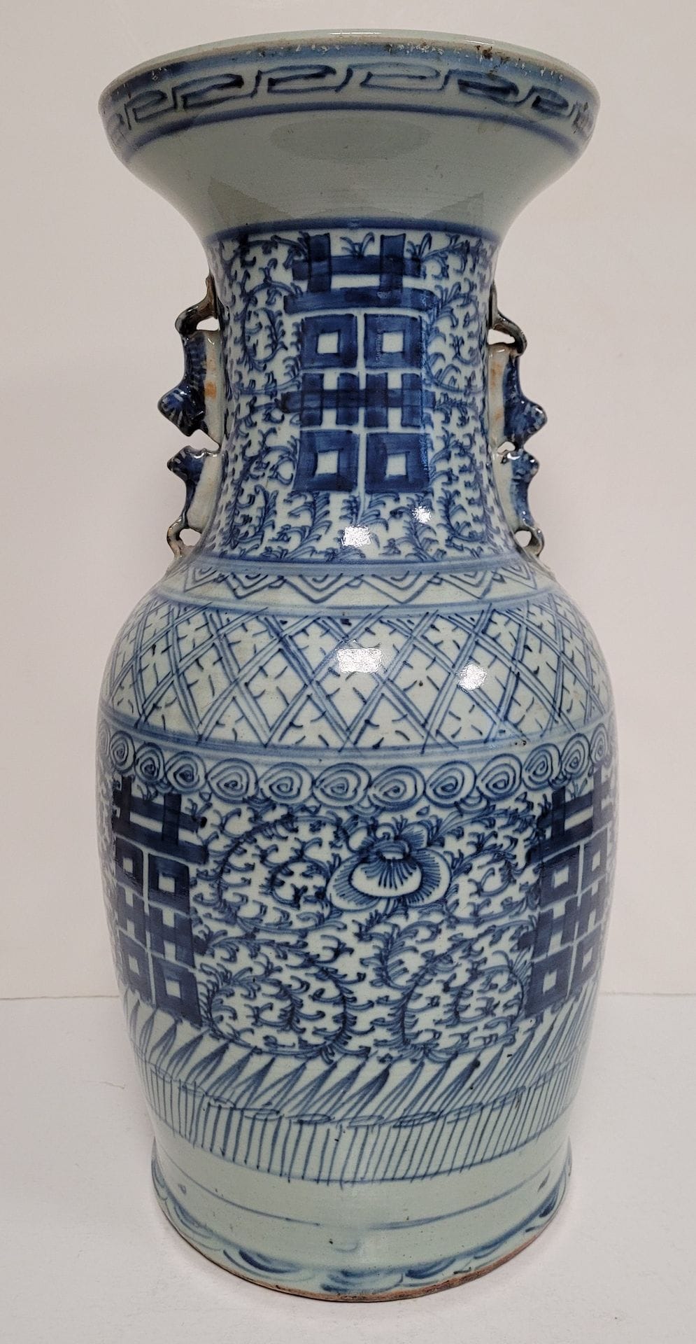 Vase en porcelaine à décor bleu blanc, Chine, XXe siècle 
A décor de caractères de double bonheur et de frises de grecques sur fond de rinceaux, prises en forme de double chimère. 
Hauteur : 44 cm
Eclat sous la base.