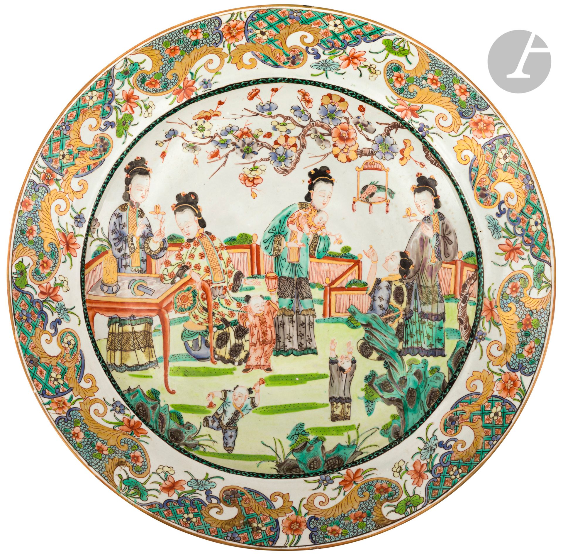 Grand plat en porcelaine dans le style de la famille verte à décor d’inspiration chinoise, Maison Samson, début XXe siècle
Émaillé en polychromie et or d’un décor central de cinq femmes, l’une assise sur un tabouret devant une table tenant un éventail, et de quatre enfants évoluant dans un jardin sous un arbre en fleurs sur la branche duquel est accroché un perchoir où se tient un oiseau. Le marli orné d’une frise de volutes, de motifs stylisés, de fleurs et végétaux. Le revers du plat montre des traces de pernettes rodées et trois branches fleuries en émail rouge sur couverte.
Diamètre : 44,7 cm
Petites égrenures en bordure.