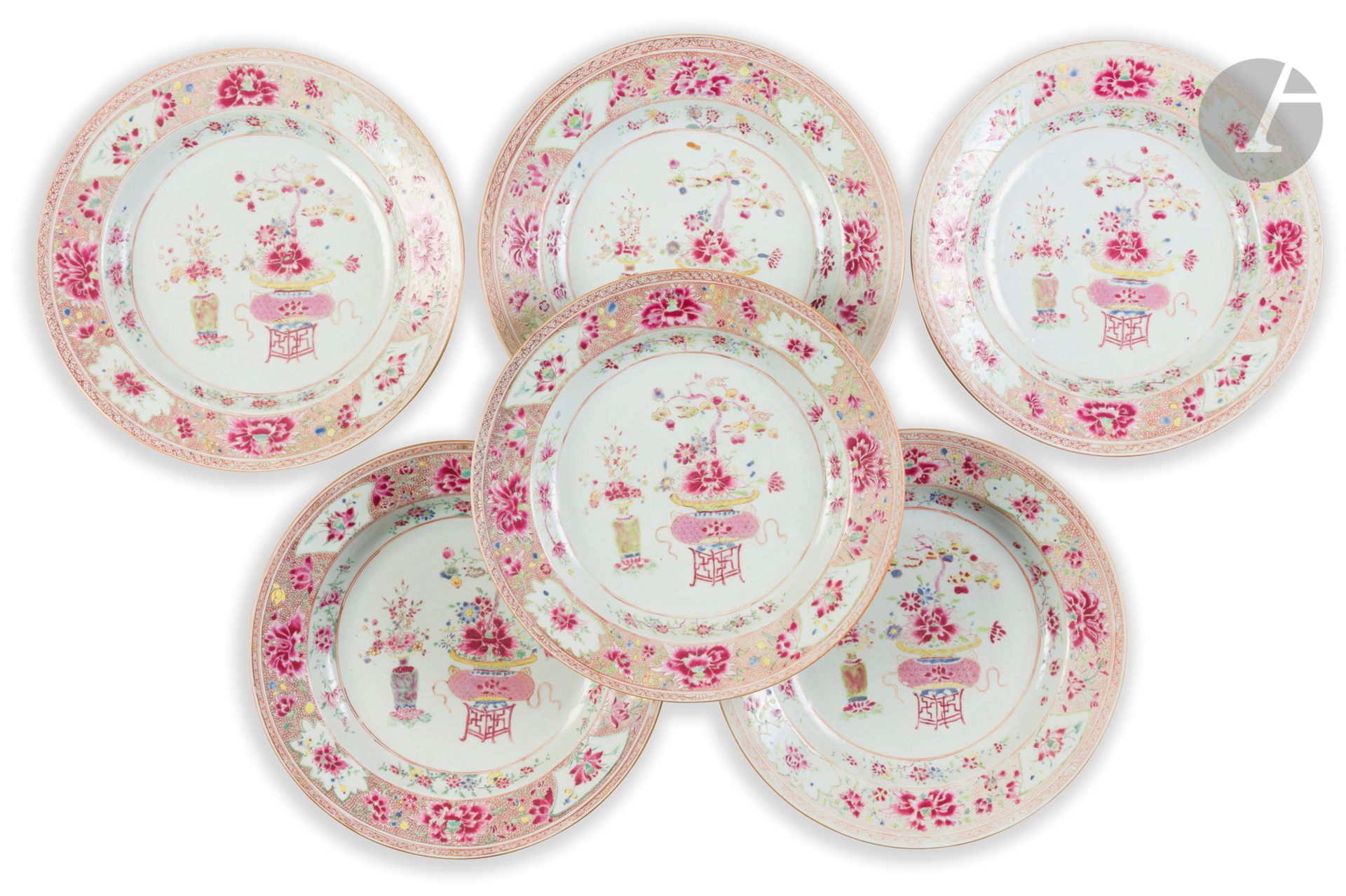 Suite de six plats ronds en porcelaine décorée en émaux de la famille rose, Chine, Compagnie des Indes, XVIIIe siècle
À décor central de deux vases fleuris de pivoines, lotus, asters, orchidées et d’un arbuste portant divers fruits (citrons digités, grenades…), la descente est ornée de quatre branches fleuries. Le marli montre quatre cartouches alternant des fleurs de lotus et de pivoines sur un fond stylisé reprenant ces mêmes fleurs. Au revers quatre fleurs de pivoine.
Diamètre : 35 cm