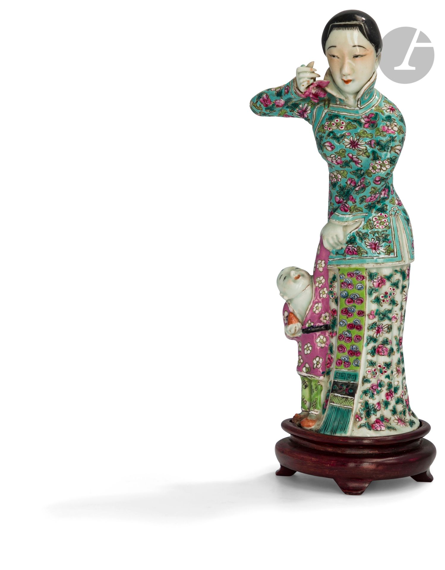 Femme à l’enfant debout en porcelaine émaillée dans le style de la famille rose, Chine, XXe siècle
La femme vêtue d’une veste de type qipao à col montant sur une jupe longue à décor floral. Elle tient une fleur d’orchidée dans la main droite et celle de l’enfant dans l’autre. Celui-ci lève la tête vers la femme et tient une pêche dans sa main droite.
Hauteur : 22,5 cm (sans socle)
Montée sur un socle en bois.