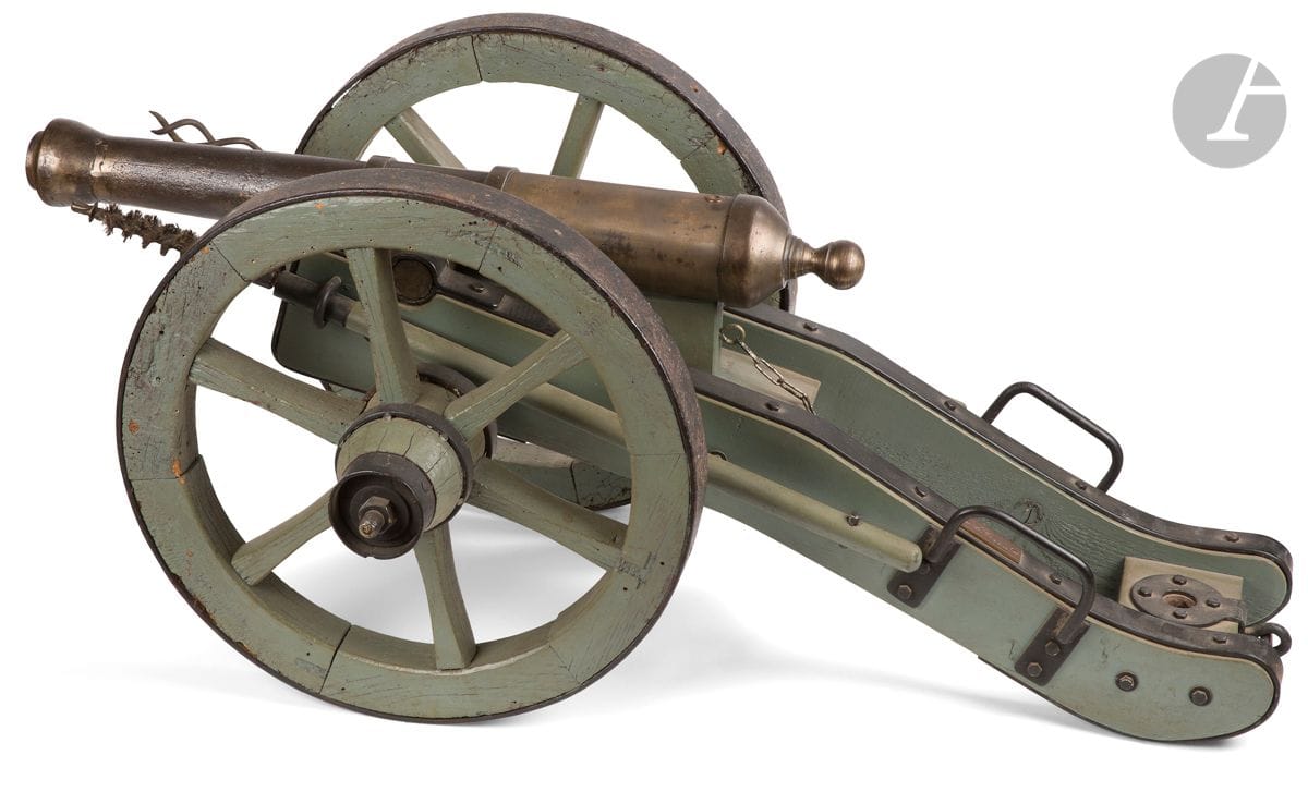 Canon de fête. 
Fût en fonte de fer, à deux anneaux de renfort. Bouche tulipée réparée. 
Affut et roues à rayons en bois laqué vert avec garnitures en fer, portant une plaque en laiton marquée « AB » et numérotée. Avec écouvillon et tire bourre. 
A.B.E. XXe siècle. 
Longueur fût : 68 cm
Hauteur : 45 cm – Longueur totale : 111 cm
