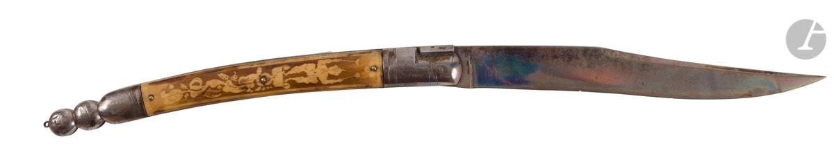 Grand couteau pliant Navaja. 
Monture en fer. Plaquettes en bois de cerf teinté à décor de personnages. 
Longueur : 45 cm 
A.B.E.