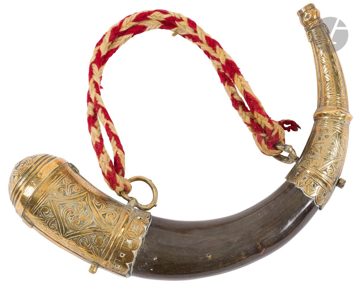 Poire à poudre d’Afrique du nord. 
En corne à deux garnitures en laiton, et deux anneaux de suspente. 
Longueur : 32 cm 
A.B.E.