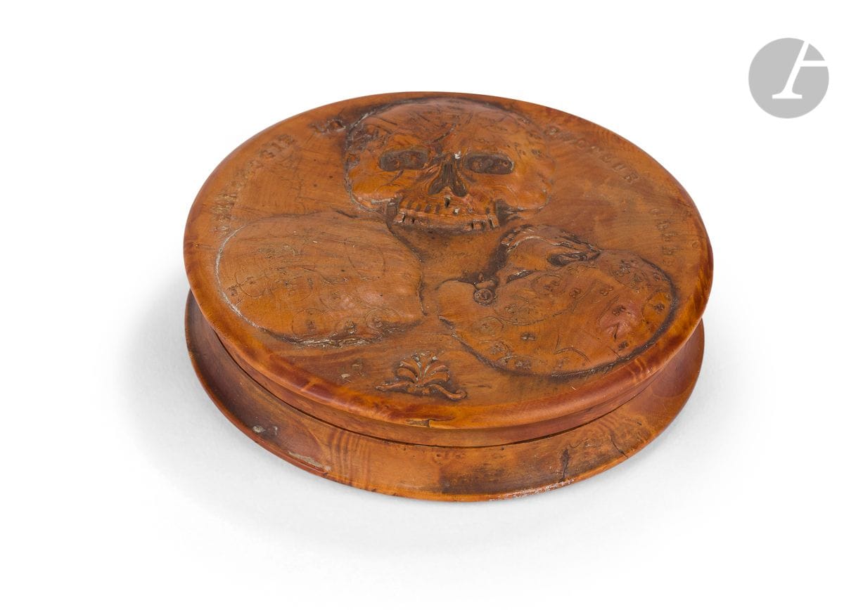 Belle boîte en loupe sculptée sur le thème de la phrénologie. 
Le couvercle est décoré de trois crânes représentant les zones d’activités de la phrénologie selon le docteur Gall ainsi que l’inscription « Craniologie du Docteur Gall ». 
Au dos sont décrites les 27 différentes zones, correspondant aux numéros des zones d’activités du couvercle avec l’inscription « Système des organes cérébraux du docteur Gall ». On peut notamment voir les organes de l’amour, de l’idée de sa race, de la mémoire (des choses, des mots…), des facultés (langue, pour les abstractions mécaniques…) du vol, de le vanité…
L’intérieur est en écaille de tortue avec quelques manques. 
Vers 1810-1830. 
D : 8 cm 
 Le docteur Franz Joseph Gall (1758-1828) est un médecin autrichien, neuro anatomiste connu pour sa méthode de dissection du cerveau. À la suite d’observations, il fonda une nouvelle discipline nommée cranioscopie ou craniologie en 1800. Cette pratique (qui cherchait à déceler les facultés des hommes grâce aux reliefs du crâne) est basée sur le principe que la morphologie du crâne humain reflétait certains traits de caractère. Par exemple Gall observa que ses meilleurs étudiants avaient des yeux protubérants. Il conclut que les déformations à la surface du crâne sont liées à la pression des organes du cerveau. Chez ceux qui ont des organes développés il y aurait, par conséquence une bosse à la surface du crâne. Ce lien entre facultés mentales et anatomie pose les fondements de la « cranioscopie » (baptisée par Gall) qui fut renommée phrénologie en 1810 par Gaspar Spurzheim, un élève de Gall.