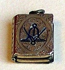 Pendentif porte photo en forme de livre qui s'ouvre. Il est finement ciselé avec le compas et le niveau en émail bleu. Fin 19è. s (2,5 cm)