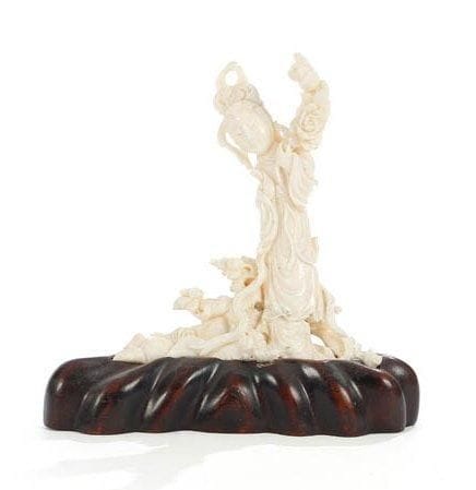 Chine, XXe siècle
Groupe en corail blanc, jeune femme debout sur un tronc d'arbre tenant une branche de pivoines. H.: 15 cm. Socle en bois