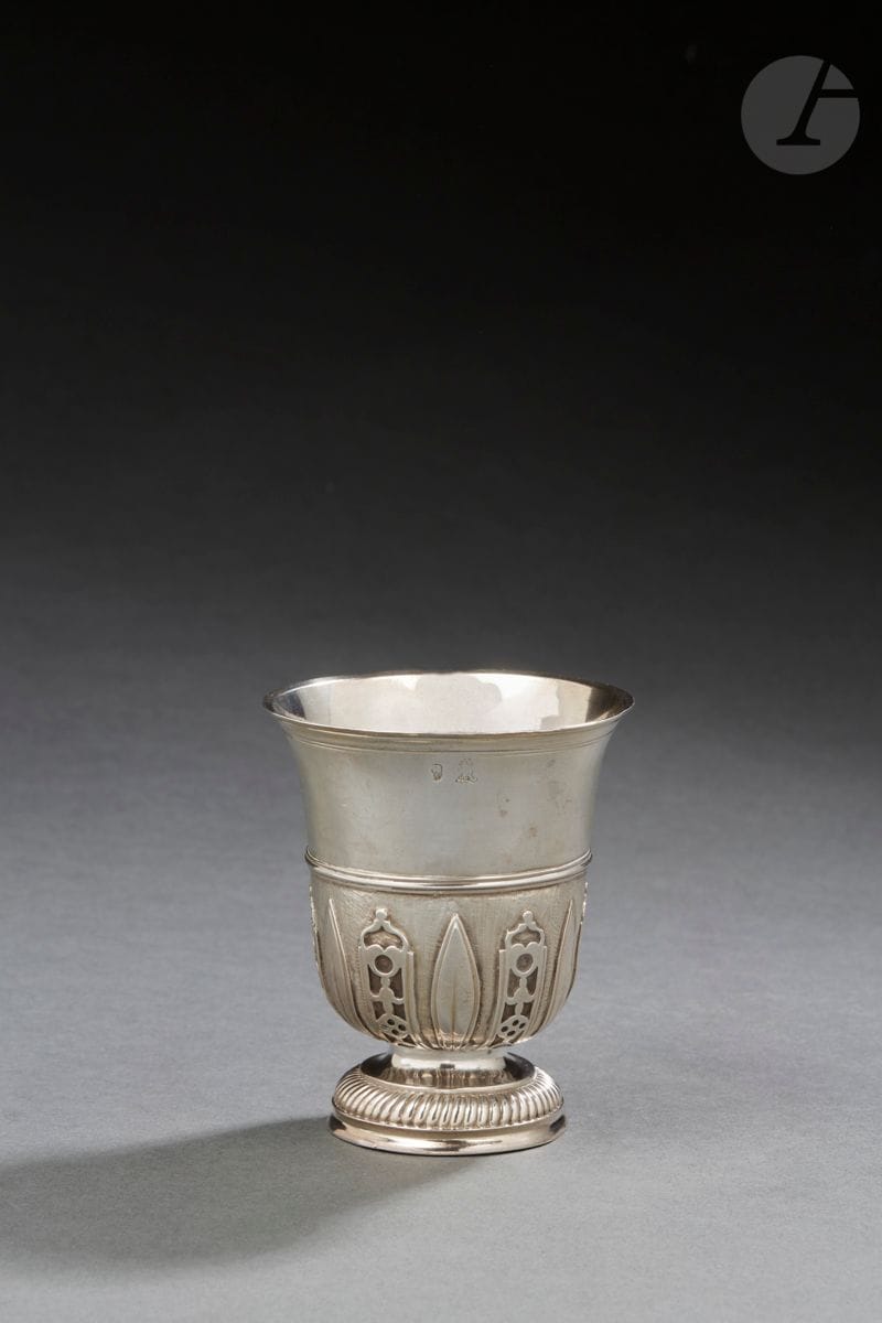 ATTRIBUÉE A LA JURIDICTION D’ORLÉANS XVIIIe SIÈCLE
Timbale tulipe à appliques en argent, le piédouche repoussé de godrons tors, gravé sur la bordure ER. Le corps est rehaussé d’appliques en alternance de lambrequins et de feuilles lancéolées sur fond amati. 
Maître orfèvre : attribuée à la famille CASTERA ou CAILLIER, non répertorié
Poids : 119 g - hauteur : 9 cm 

JURIDICTION OF ORLEANS
A silver tulip-shaped beaker.
Master silversmith: attributed to CASTERA or CAILLIER family, unlisted