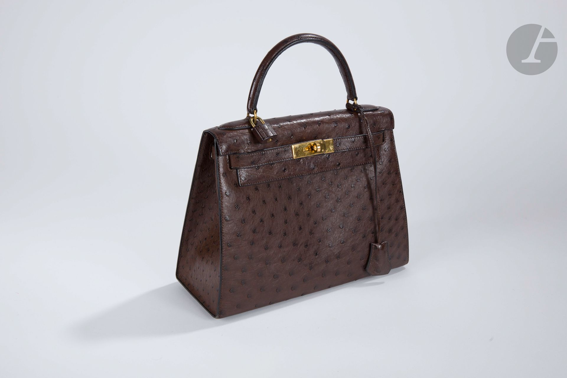 HERMèS Paris Made in France

Kelly bag saddler 28 in brown ostrich, gold metal trim, shoulder strap, padlock, bell, two keys, cover and box. Year 1988.