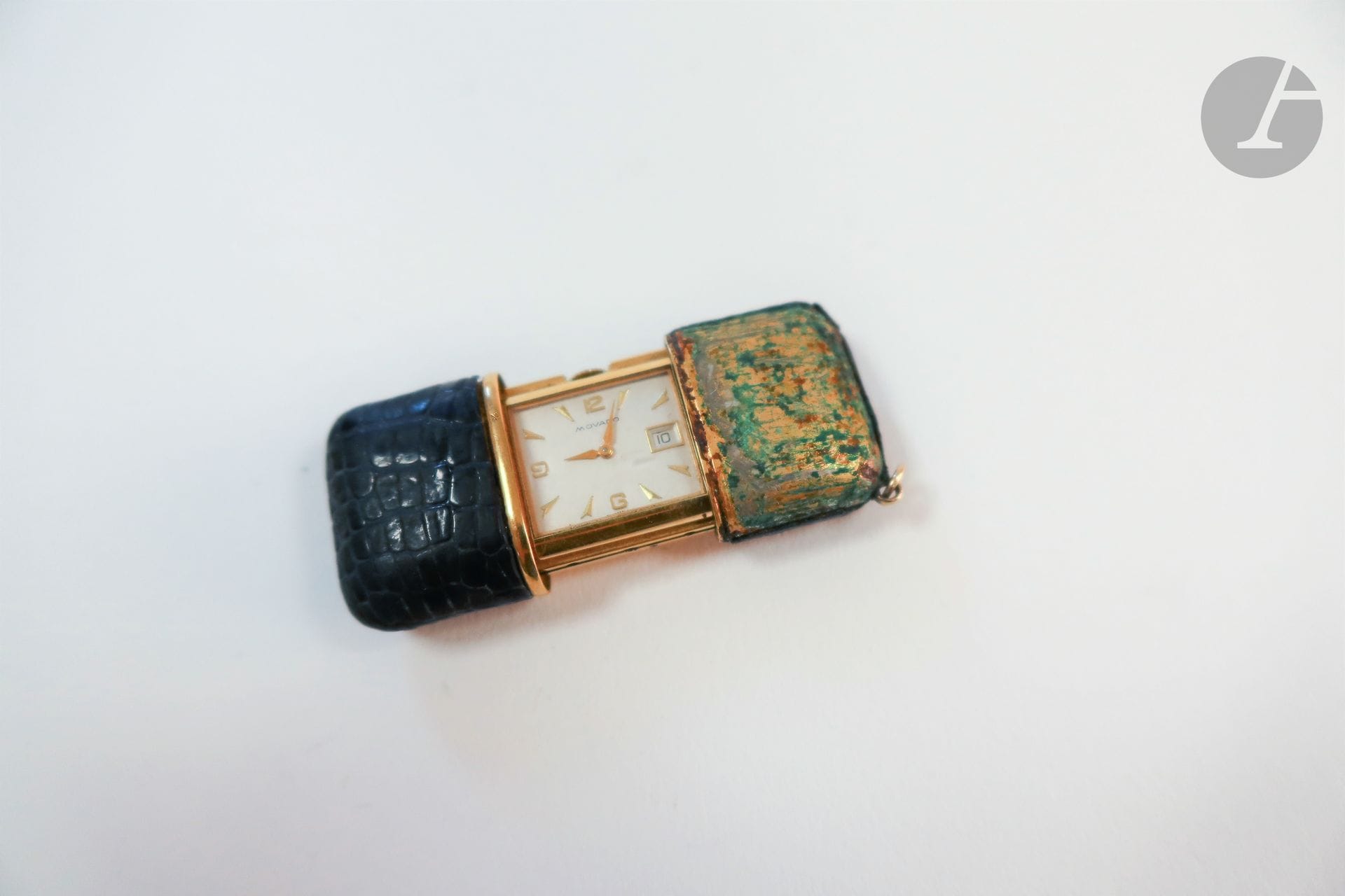 MOVADO Ermeto vers 1960

Montre de sac en métal doré formant pendulette, cadran blanc, date par guichet à 3H, mouvement à remontage mécanique. Boîtier garni de cuir (manque et accident). La montre est accompagnée de son écrin d'origine.