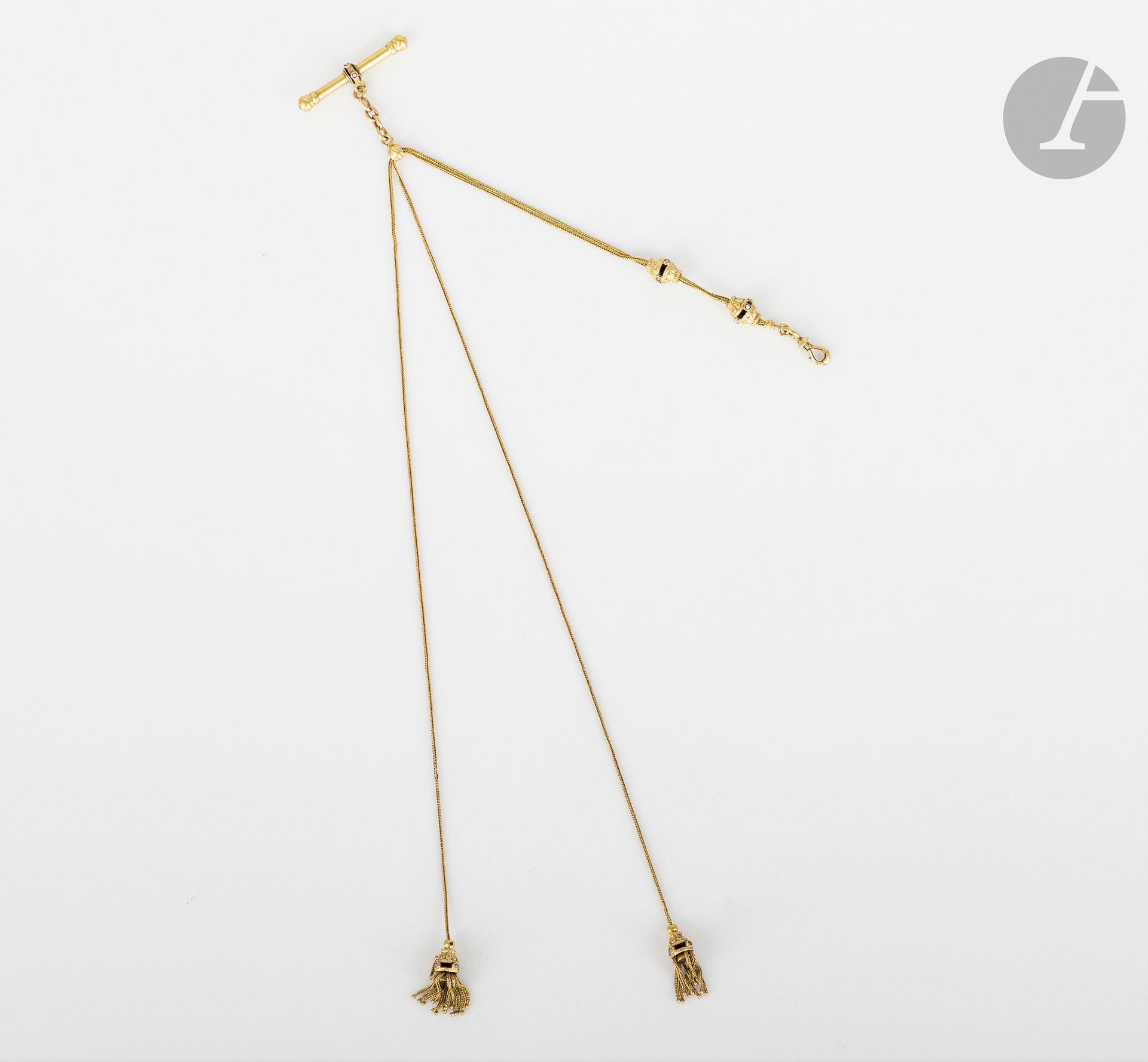Chaîne de montre en or 18K (750) munie de passants et de pompons agrémentés d'émail et de demi-perles. Travail français de la fin du XIXe siècle. Poids brut : 17,2 g (manques)