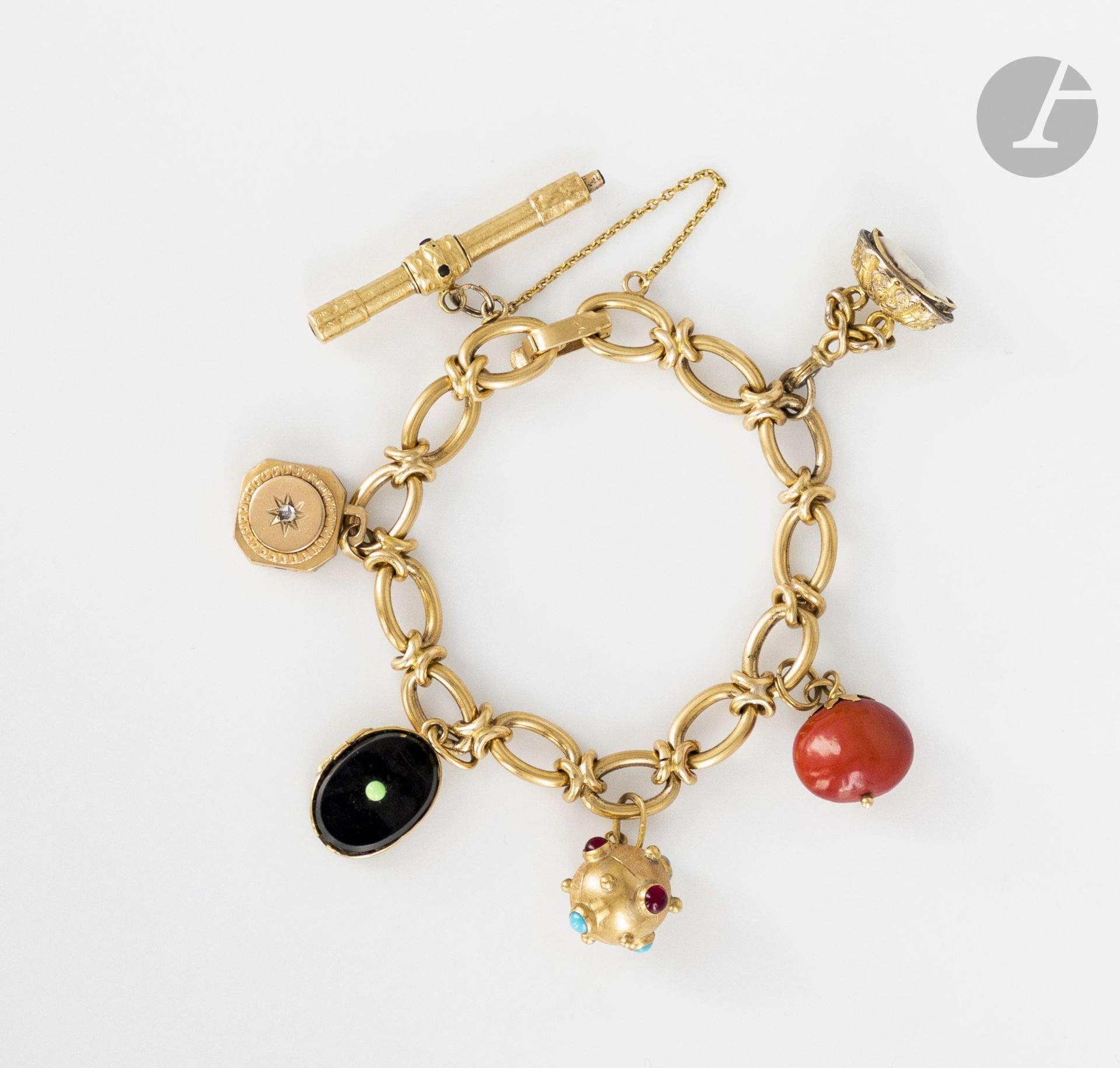 Bracelet en or 18K (750), orné de 6 pampilles en or 18K, 14K ou 9K : un porte-mine, deux médaillons porte-souvenirs, une sphère sertie de pierres de couleurs cabochons, un fruit en corail et un camée. Poids brut : 45,3 g (égrisures, enfoncements)