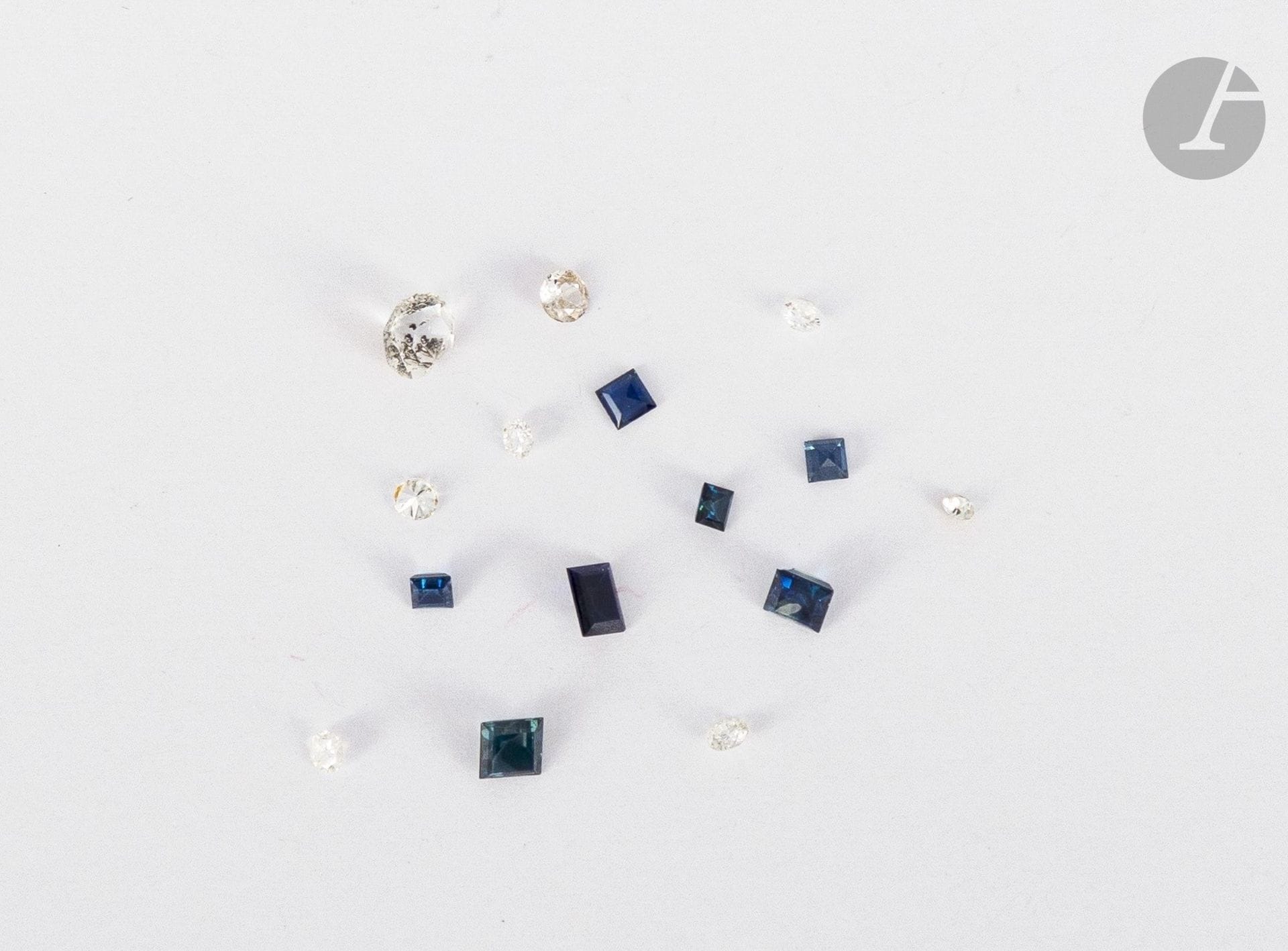 Lot de pierres variées (diamants, saphirs synthétiques, diamants imitation) sur papier.