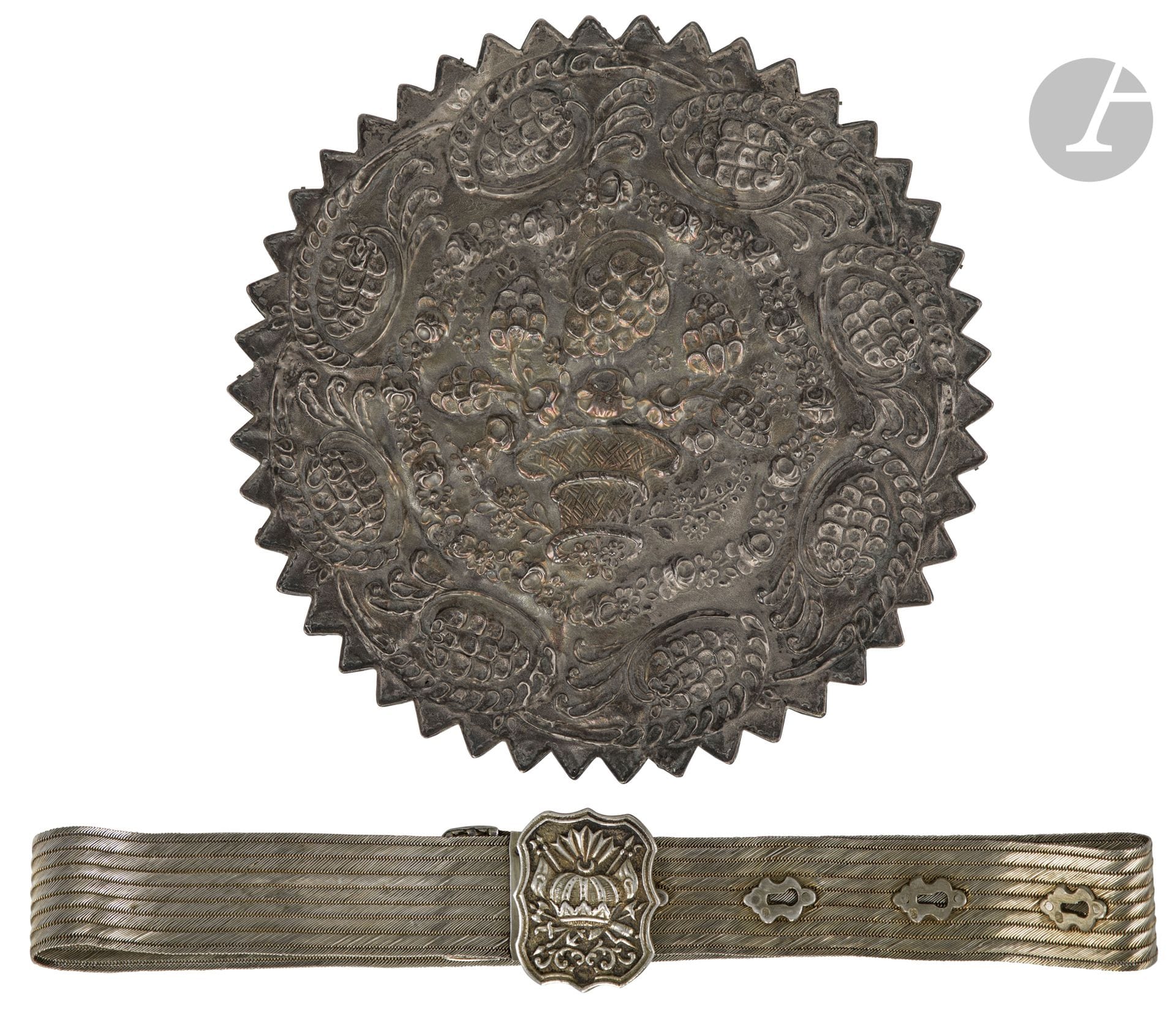 Ceinture en vermeil, Empire ottoman, XIXe siècle
Ruban en neuf bandeaux de vermeil tressé avec boucle chantournée aux armoiries ottomanes, quatre perforations en forme de serrure, et extrémité polylobée à décor d’alvéoles. Plusieurs poinçons, tughra, probablement celle de Mahmoud II (r.1808-1839) sur la boucle, et sah sur les perforations.
Longueur : 81,6 cm ; poids brut : 480 g
On joint un miroir étoilé en argent à décor repoussé d’une corbeille de fleurs et de pommes de pin, Empire ottoman, début XIXe siècle. Poinçonné d’une tughra, probablement celle de Mahmoud II (r.1808-1839). D. : 24 cm ; P.B. : 472 g ; accidents et déformations, glace remplacée, ainsi qu’une paire de ciseaux de calligraphe en acier damasquiné, Empire ottoman, XIXe siècle ; L. : 24,9 cm ; un anneau de prise déformé, traces de rouille.

A silver-gilt belt, a silver mirror, a pair of calligrapher’s scissors, Ottoman Turkey, 19th century