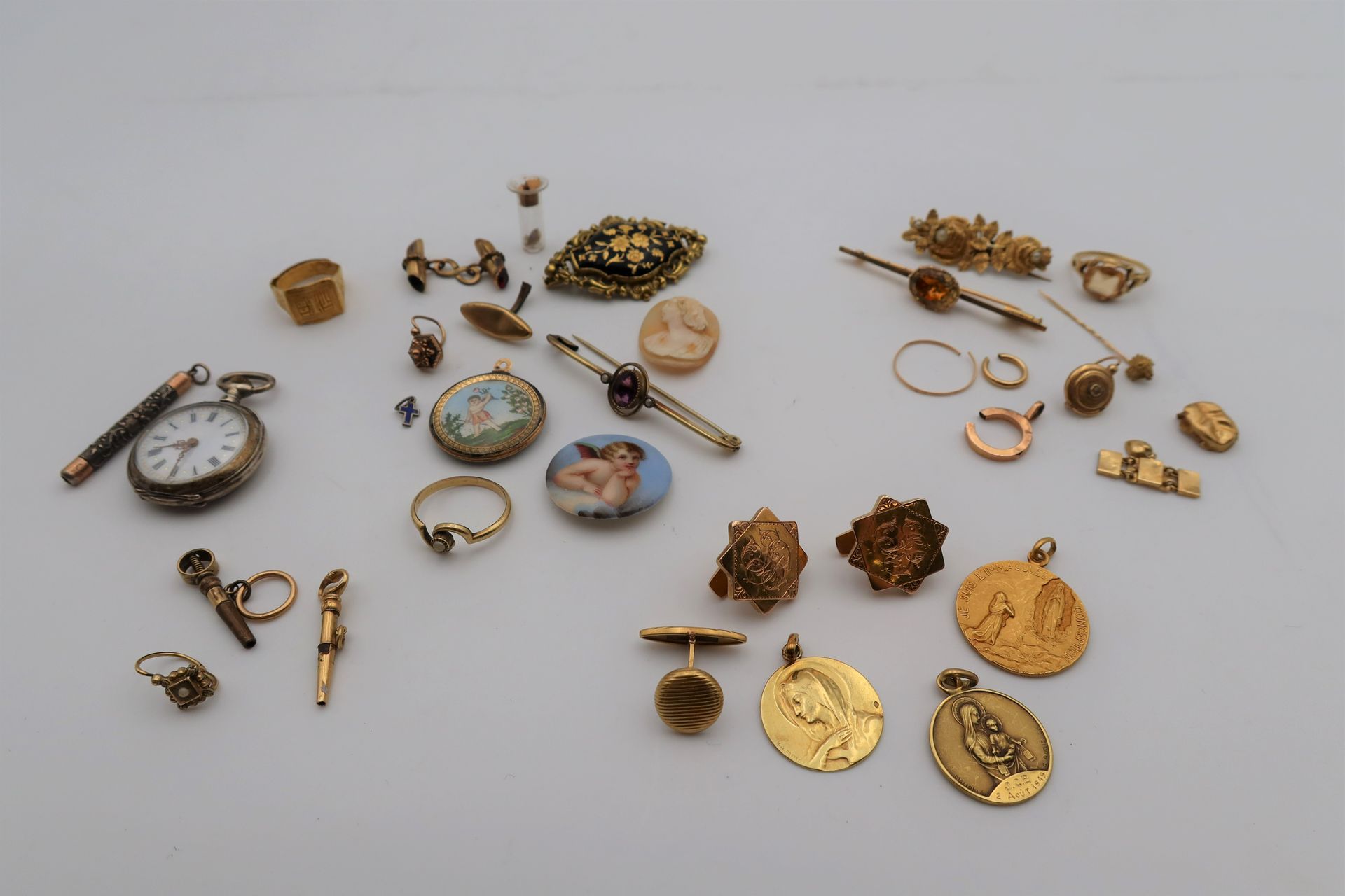 Lot de bijoux et bris, majoritairement en or:
- 3 médailles religieuses et 3 boutons de manchette, en or (18K). Poids: 23,3 g
- 2 broches, 1 bague, 1 boucle d'oreille et des bris d'or (18K). Poids brut: 17,7 g
- 1 chevalière en or (24K). Poids: 7,1 g
- 1 petite montre de col en argent (double paroie), sylet et croix émaillée.  Poids brut: 26,3 g
-  2 clefs de montre et 1 boucle d'oreille en or et plaqué. Poids brut: 3,9 g
On joint un lot de bijoux en métal doré et autres materiaux. 
